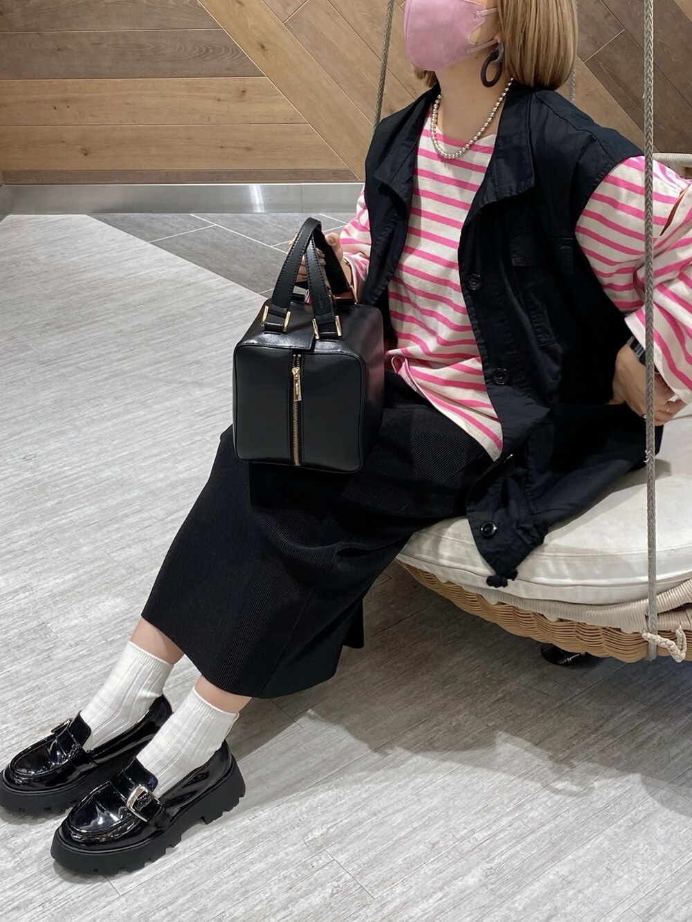 ブラック系のベスト、ピンク系のTシャツ/カットソー、ブラック系のハンドバッグを着用したレディースの秋コーディネートの5枚目の写真