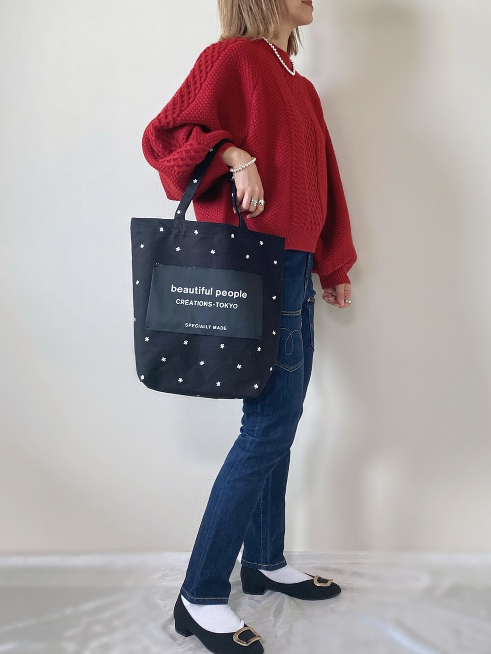 レッド系のニット/セーター、ブラック系のトートバッグ、ブラック系のシューズを着用したレディースの冬コーディネートの2枚目の写真