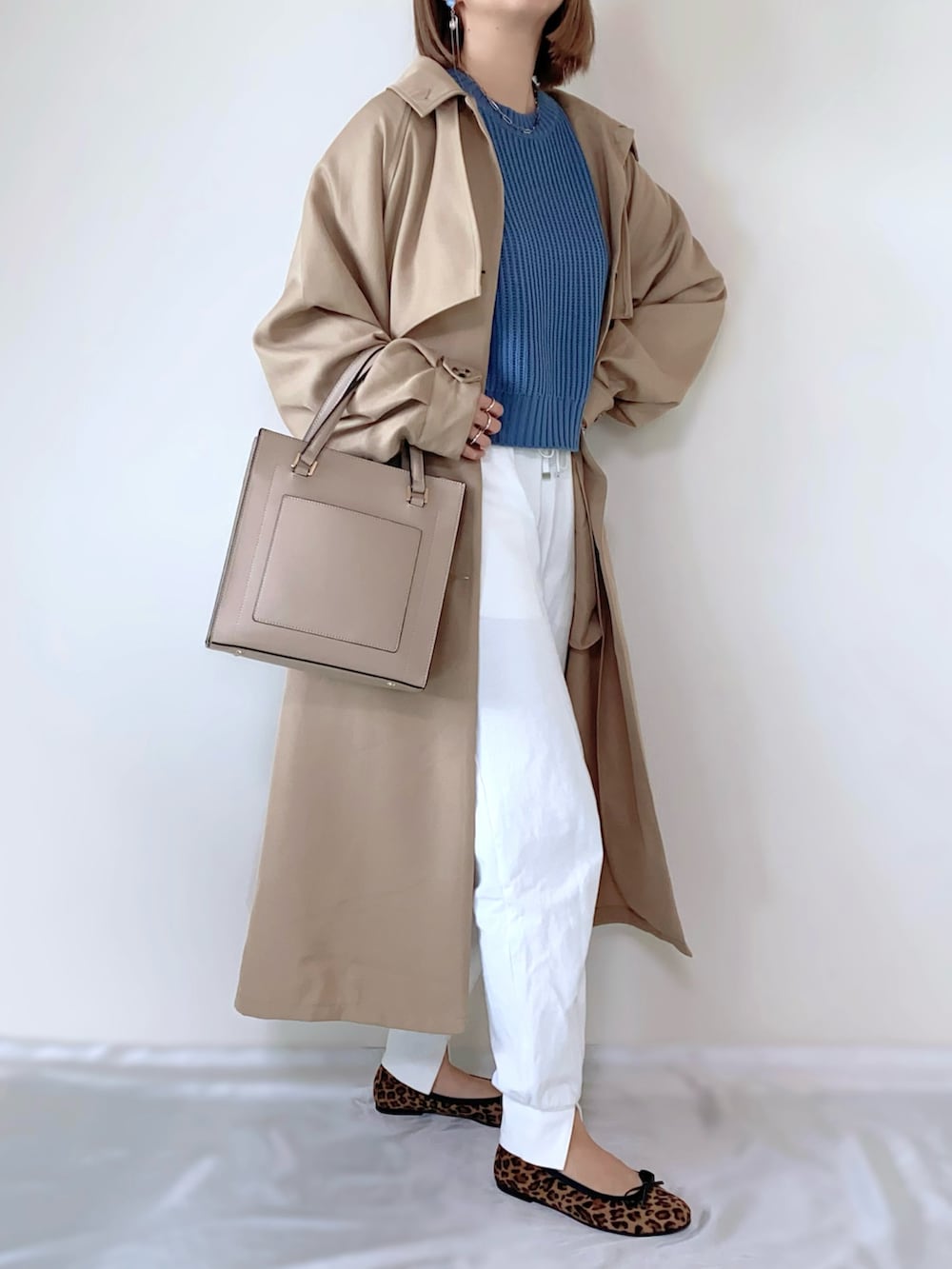ブルー系のニット/セーター、ホワイト系のその他パンツ、ベージュ系のバッグを着用したレディースの春コーディネートの2枚目の写真