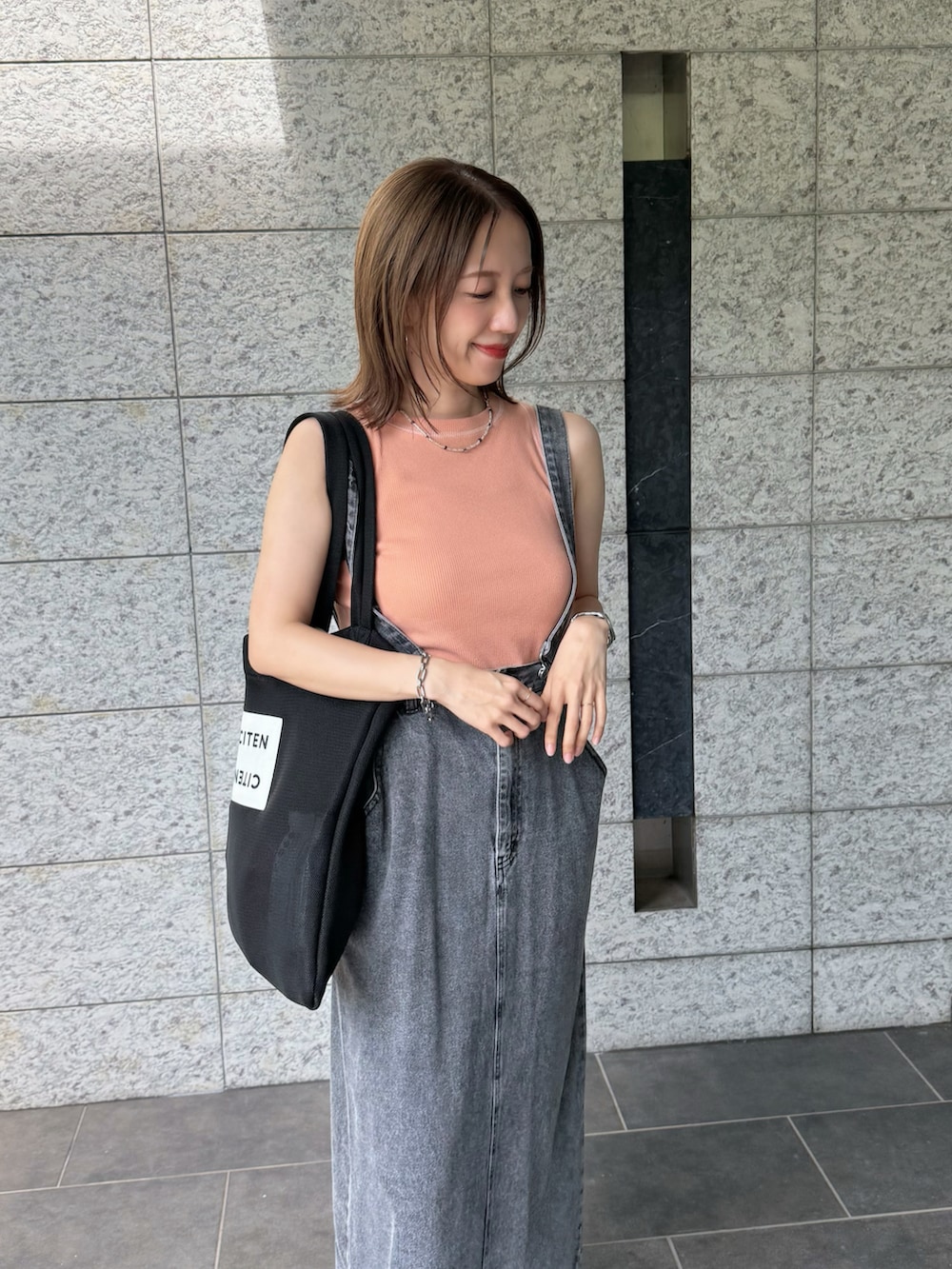 ブラック系のサンダル、ピンク系のTシャツ/カットソー、ブラック系のジャンパースカートを着用したレディースの夏コーディネートの3枚目の写真