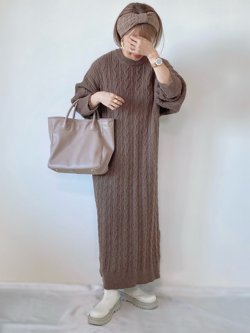 ベージュ系のバッグ、ブラウン系のワンピース、ホワイト系のブーツを着用したレディースの秋コーディネートの2枚目の写真
