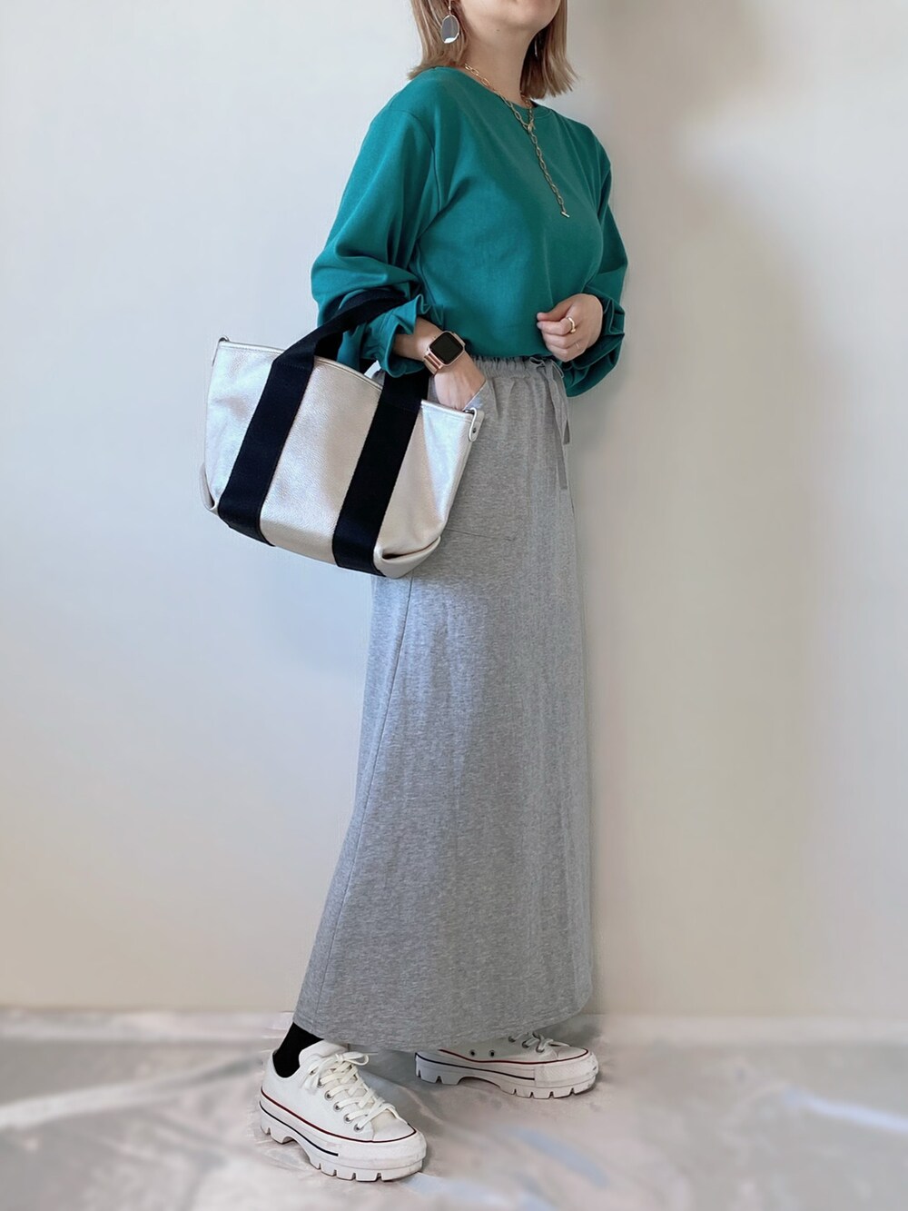 グリーン系のTシャツ/カットソー、シルバー系のトートバッグ、グレー系のスカートを着用したレディースの春コーディネートの2枚目の写真