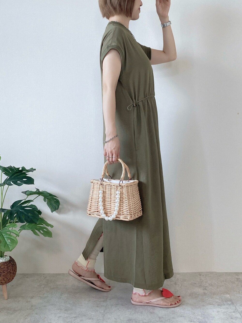 ベージュ系のかごバッグ、グリーン系のワンピース、ピンク系のサンダルを着用したレディースの夏コーディネートの2枚目の写真