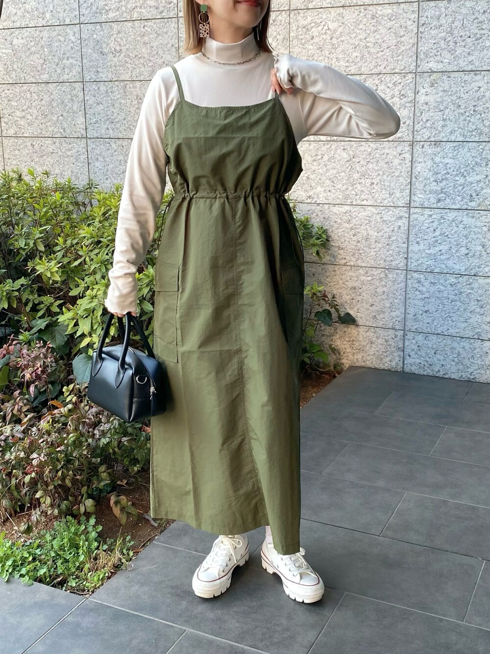 ブラック系のバッグ、グリーン系のワンピース、ホワイト系のスニーカーを着用したレディースの春コーディネートの3枚目の写真