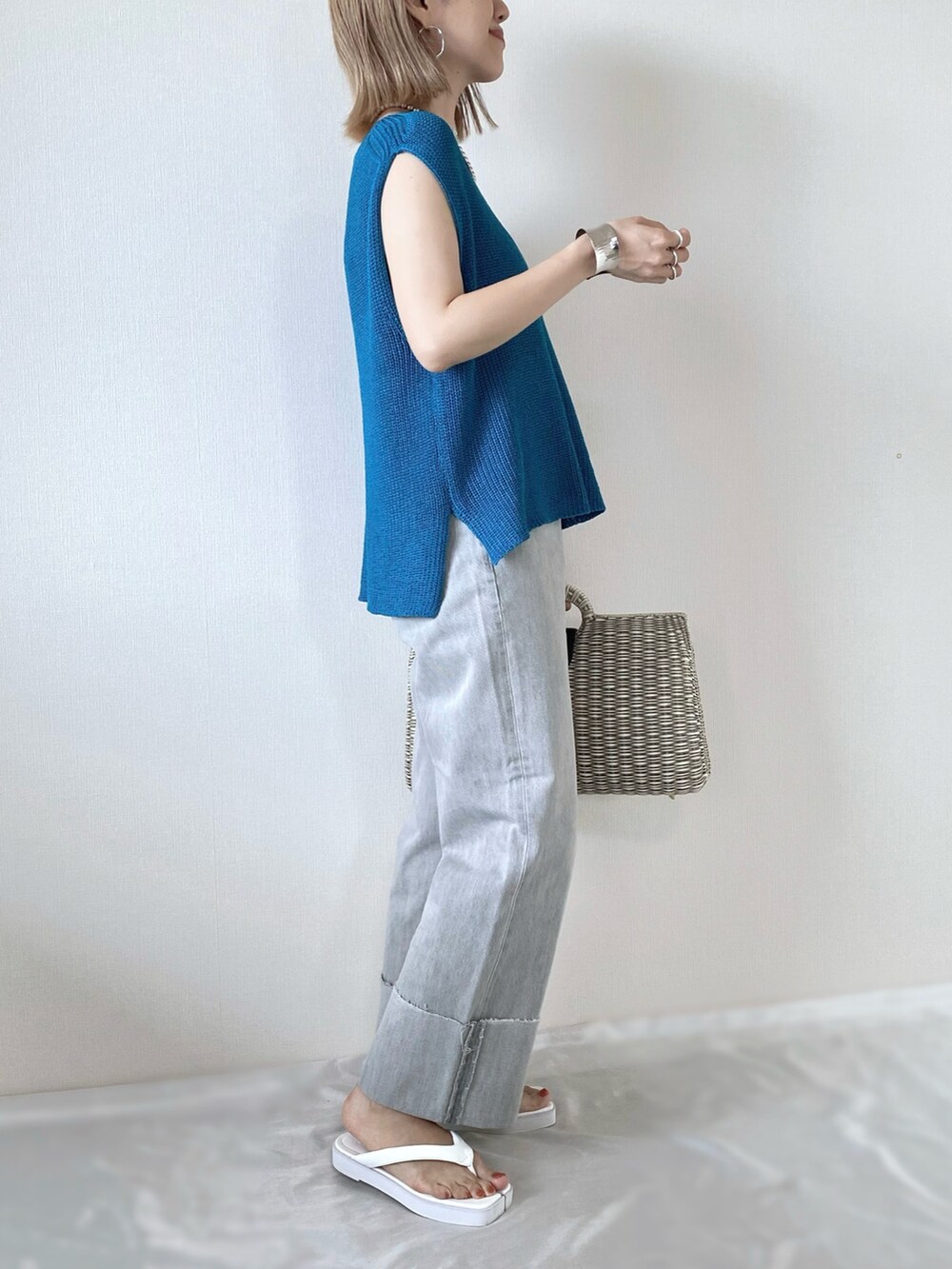 ブルー系のベスト、グレー系のデニムパンツ、ホワイト系のサンダルを着用したレディースの夏コーディネートの2枚目の写真