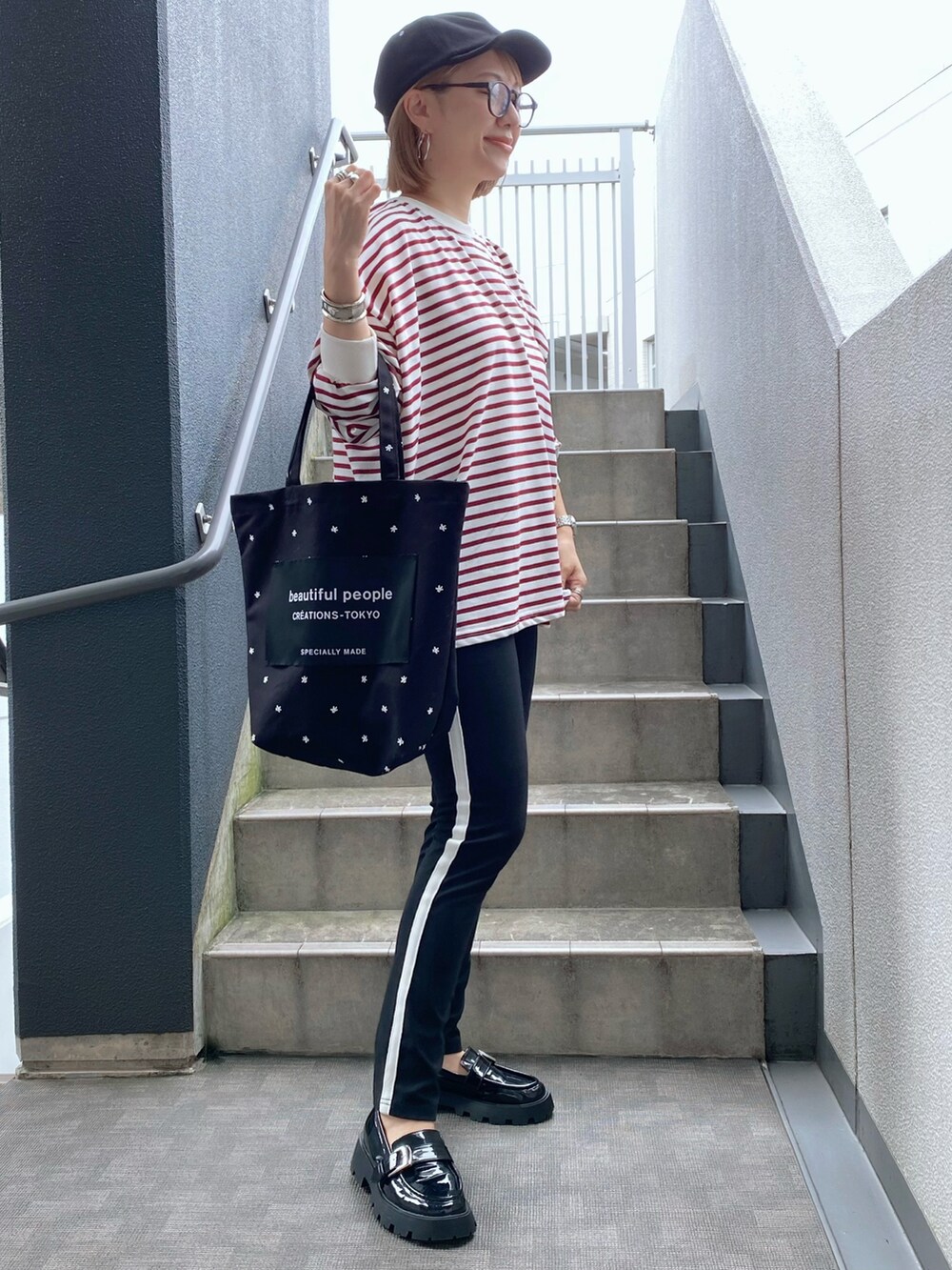 レッド系のTシャツ/カットソー、ブラック系のトートバッグ、ブラック系のローファーを着用したレディースの秋コーディネートの2枚目の写真