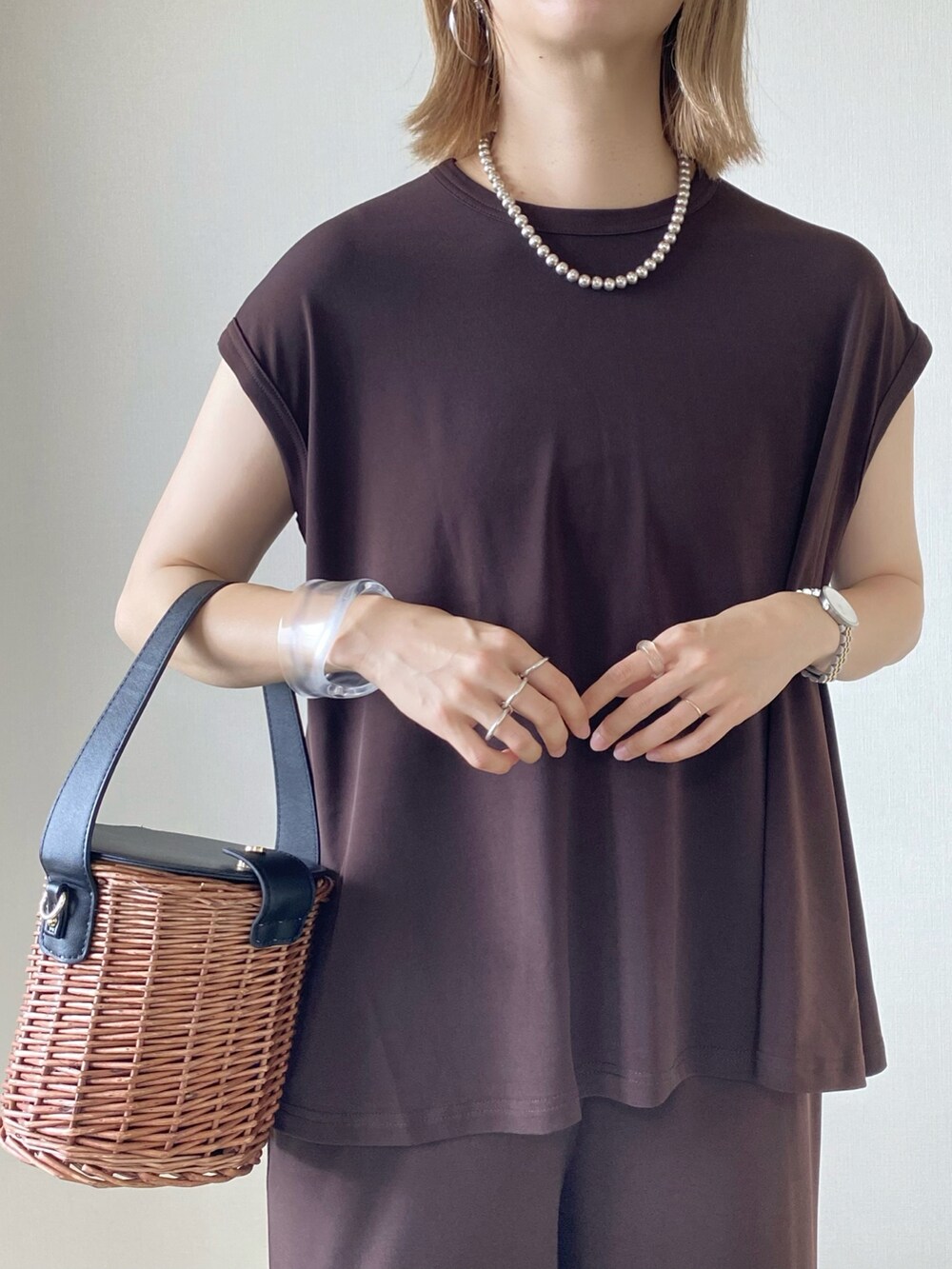 ブラック系のバッグ、ホワイト系のサンダル、ブラウン系のその他トップスを着用したレディースの夏コーディネートの4枚目の写真