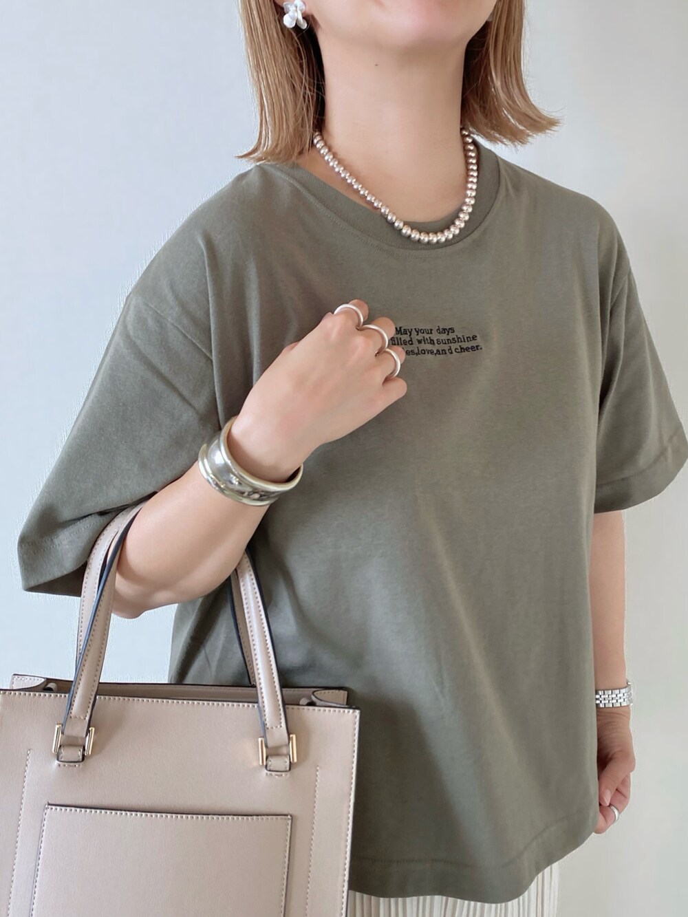グリーン系のTシャツ/カットソー、ベージュ系のバッグ、ホワイト系のパンツを着用したレディースの夏コーディネートの5枚目の写真