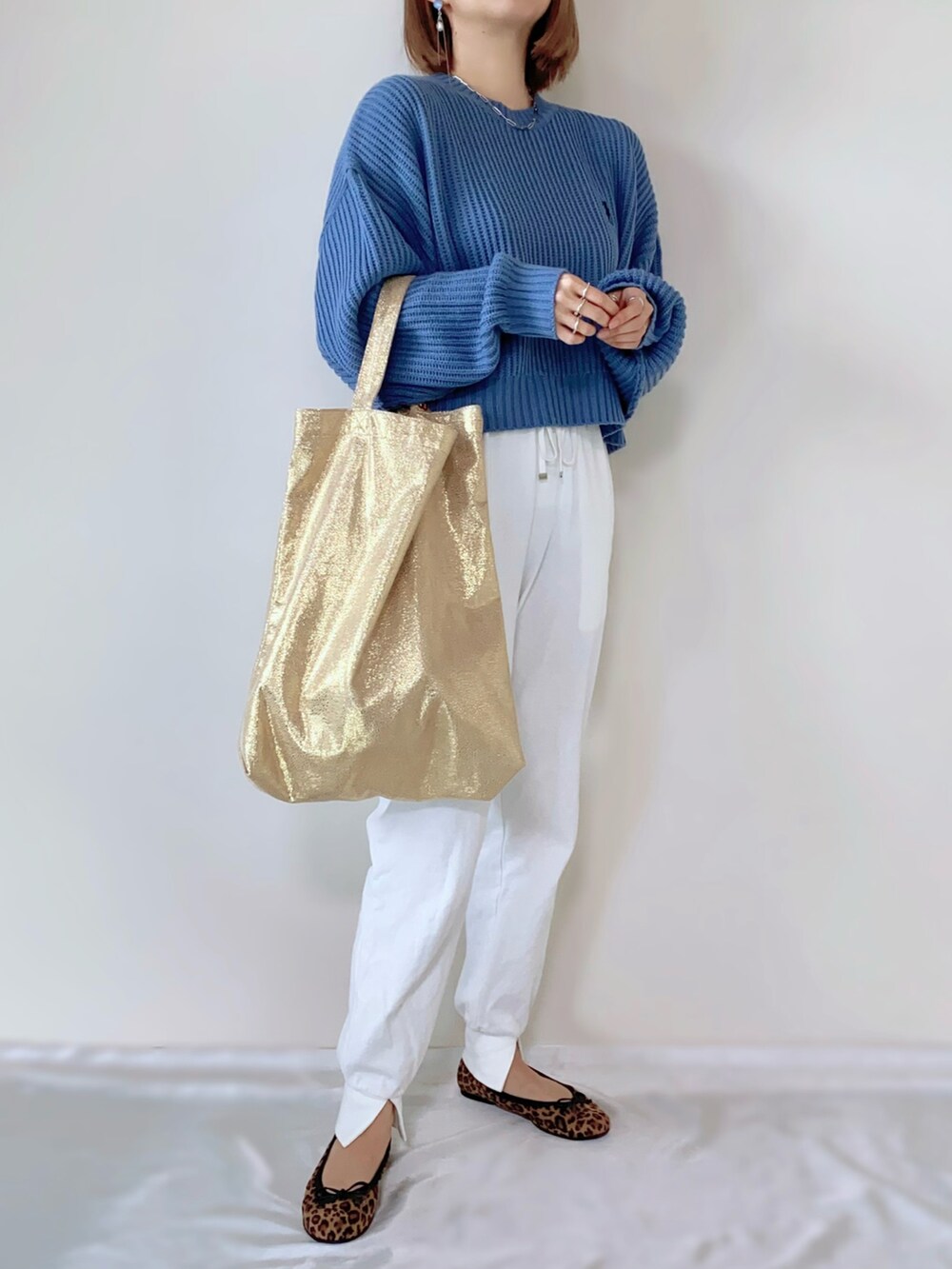 ゴールド系のトートバッグ、ホワイト系のその他パンツ、ブルー系のニット/セーターを着用したレディースの春コーディネートの3枚目の写真