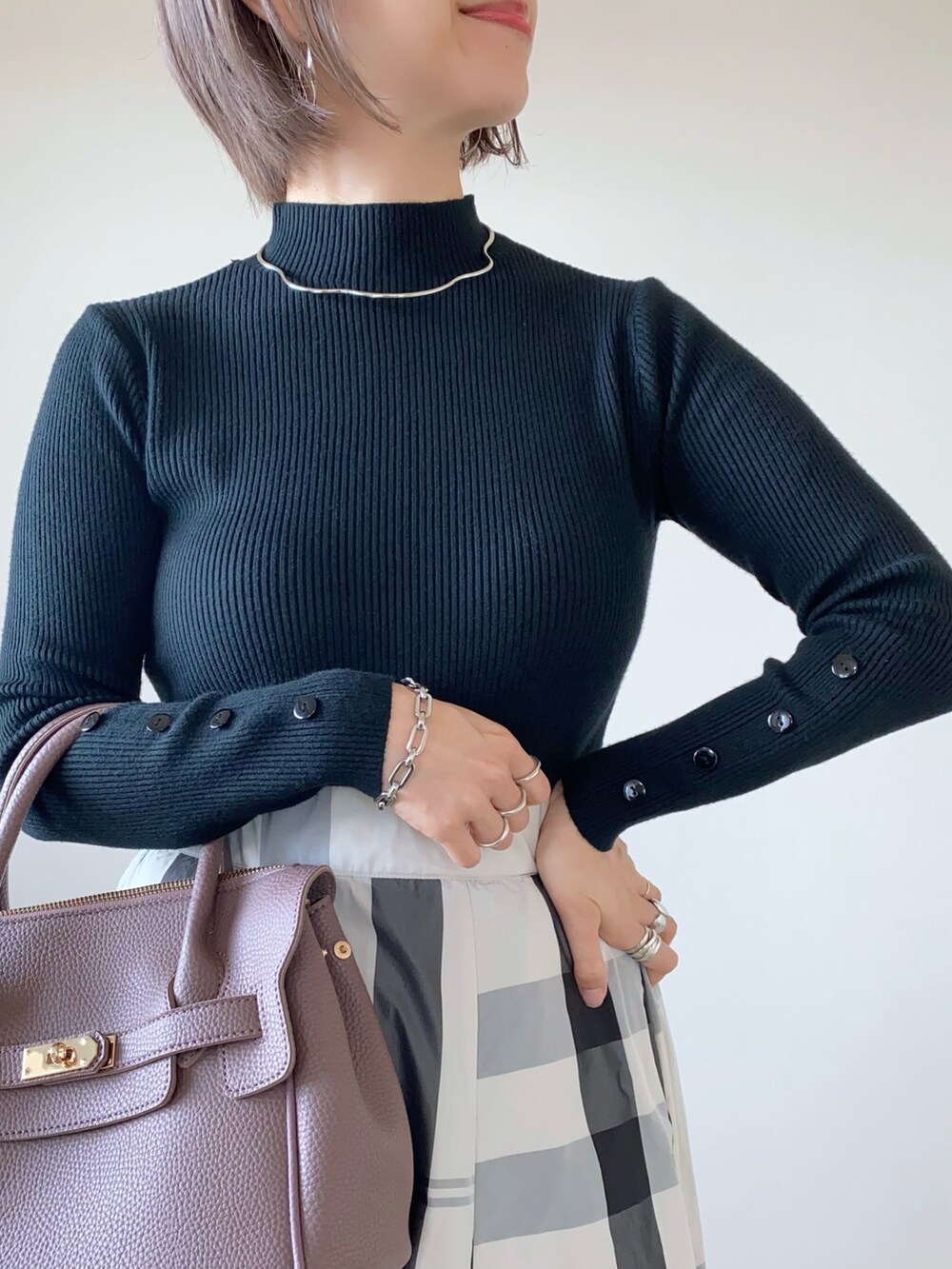 ホワイト系のスカート、ブラック系のニット/セーター、シルバー系のネックレスを着用したレディースの秋コーディネートの3枚目の写真