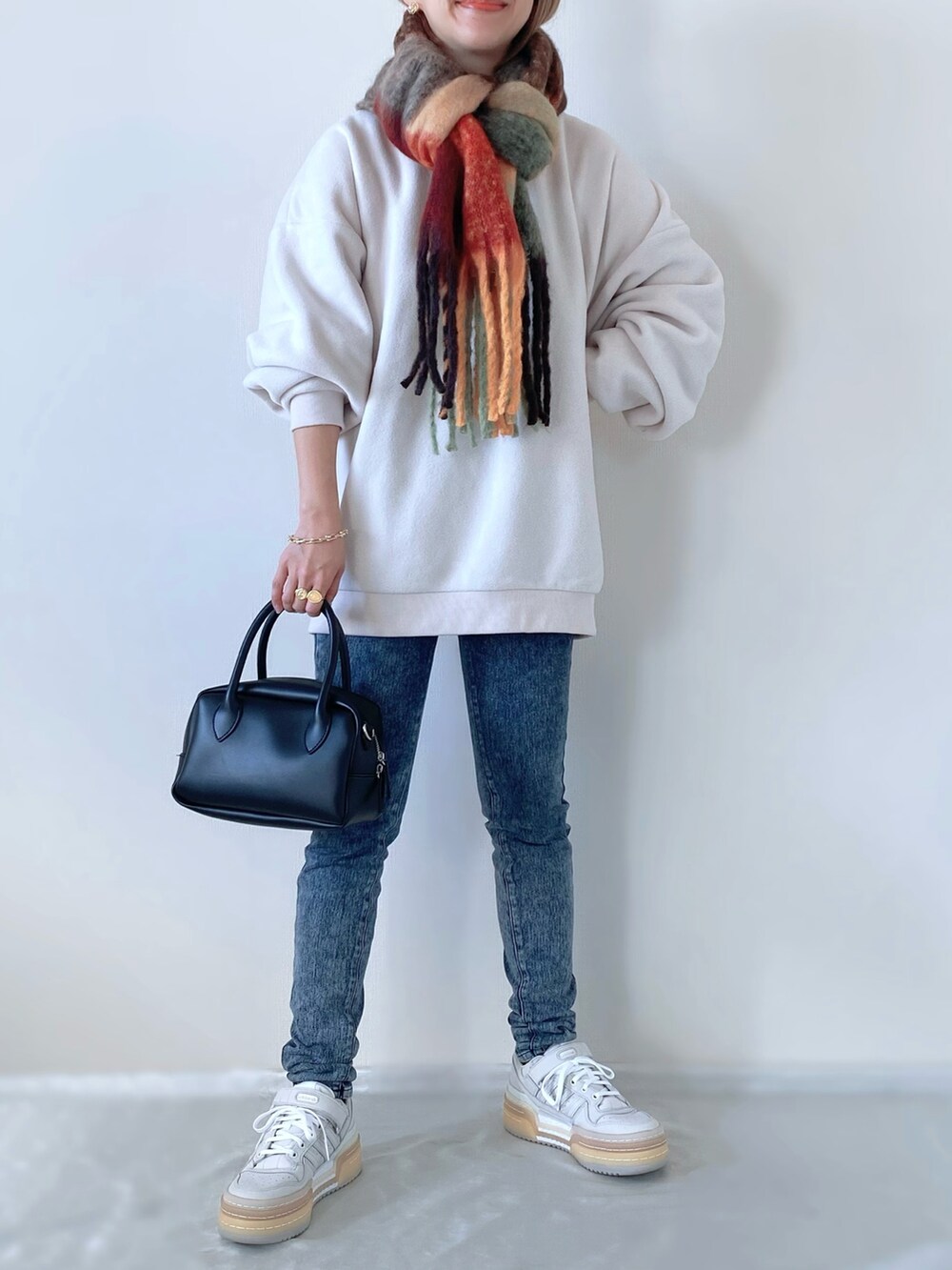 ホワイト系のスウェット、ホワイト系のスニーカー、ブラック系のバッグを着用したレディースの冬コーディネートの3枚目の写真
