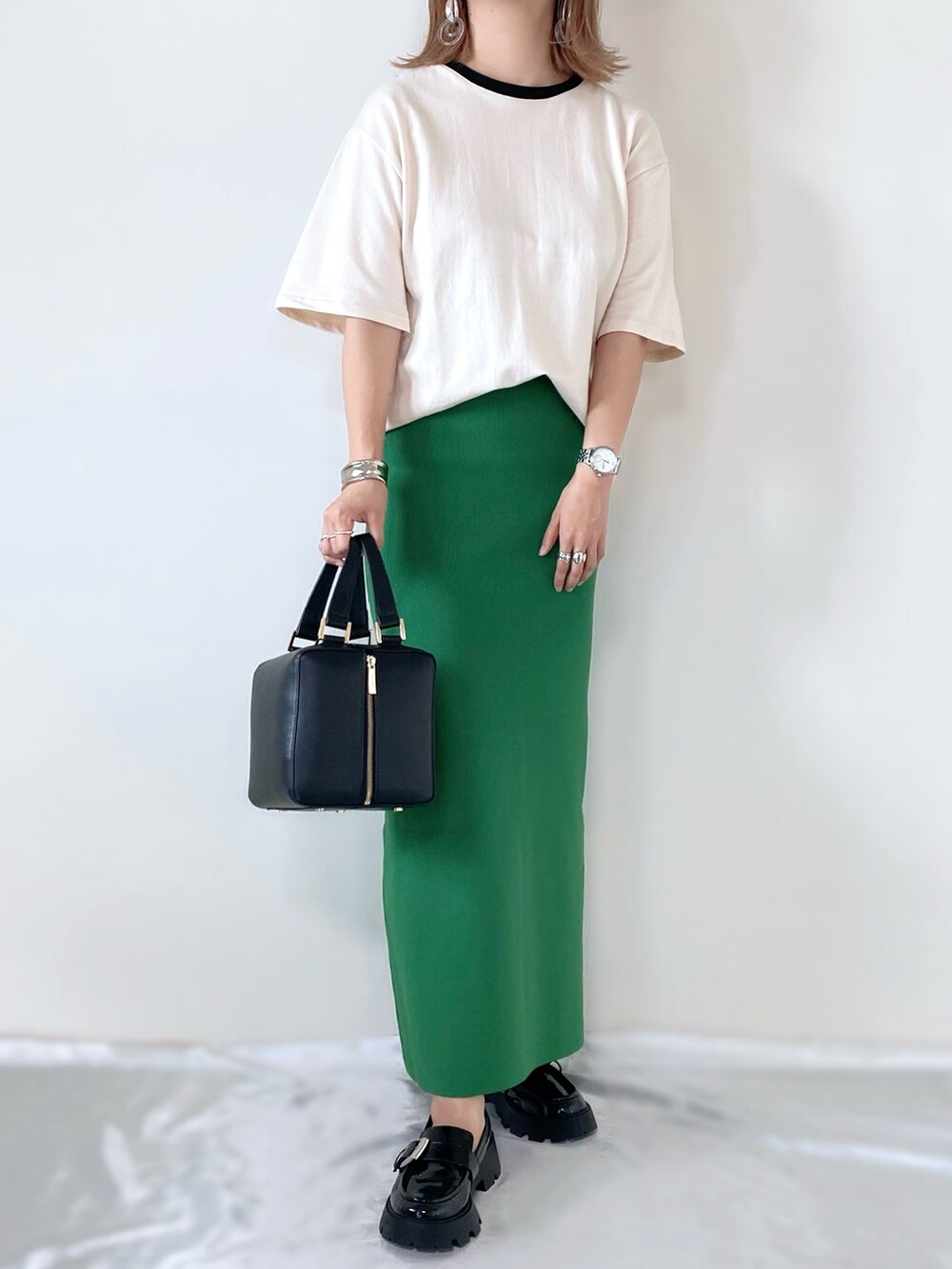 ブラック系のハンドバッグ、ベージュ系のTシャツ/カットソー、グリーン系のスカートを着用したレディースの秋コーディネートの2枚目の写真