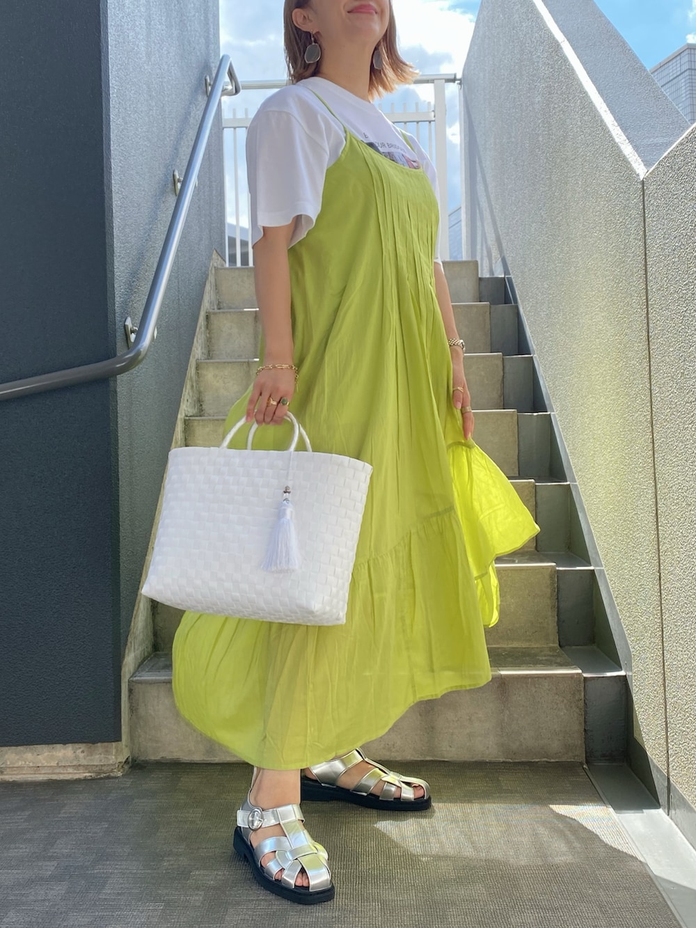 イエロー系のワンピース、ホワイト系のかごバッグ、ホワイト系のTシャツ/カットソーを着用したレディースの夏コーディネートの2枚目の写真