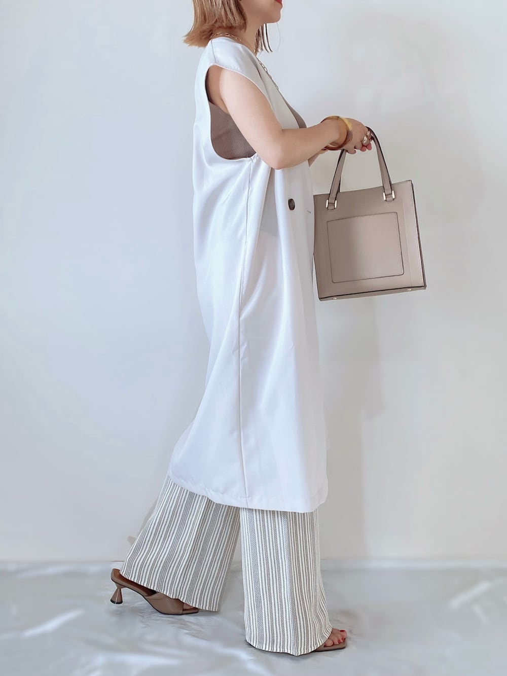 ホワイト系のその他パンツ、ホワイト系のベスト、ベージュ系のバッグを着用したレディースの夏コーディネートの2枚目の写真