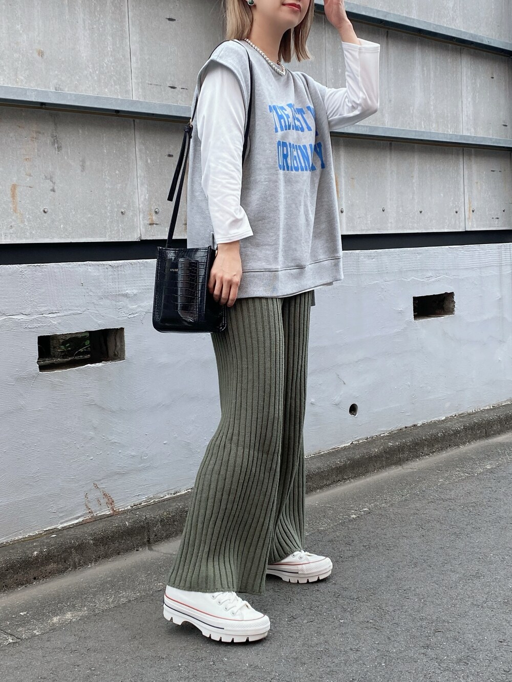 グレー系のベスト、ホワイト系のTシャツ/カットソー、ブラック系のバッグを着用したレディースの冬コーディネートの2枚目の写真