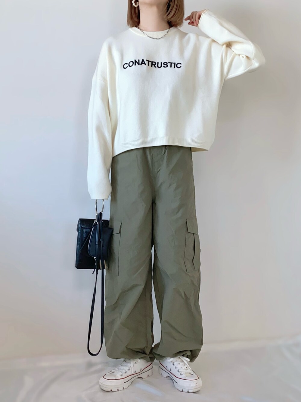 グリーン系のカーゴパンツ、ブラック系のショルダーバッグ、ホワイト系のスニーカーを着用したレディースの春コーディネートの2枚目の写真
