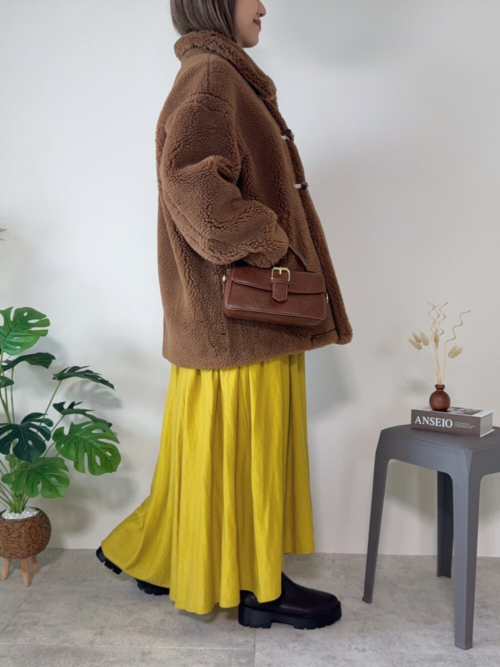 ブラウン系のムートンコート、ブラウン系のハンドバッグ、ブラウン系のブーツを着用したレディースの秋コーディネートの4枚目の写真