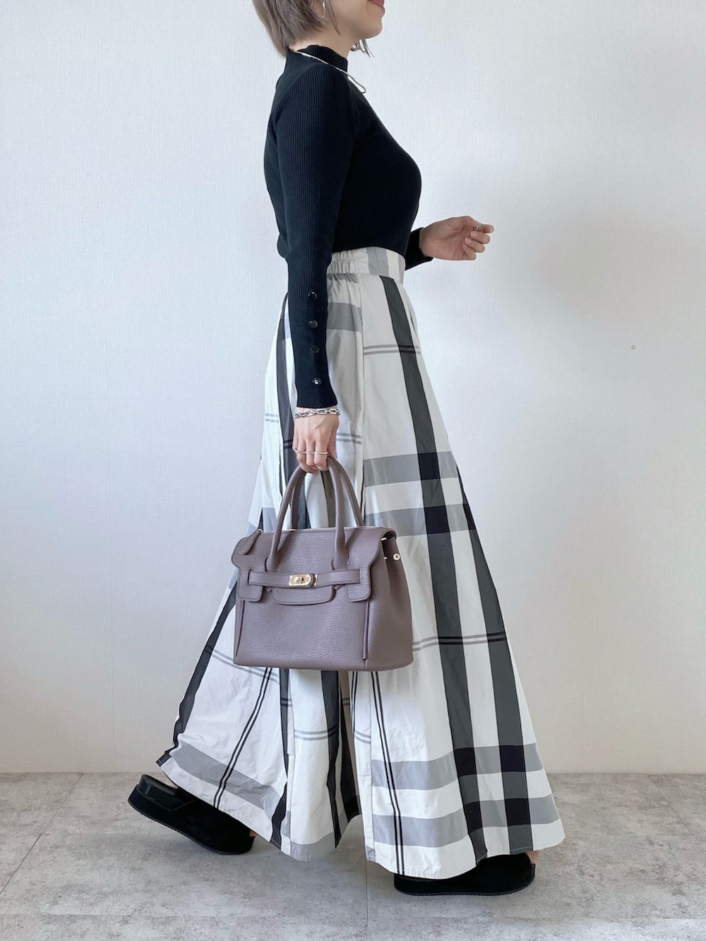 ホワイト系のスカート、ブラック系のニット/セーター、シルバー系のネックレスを着用したレディースの秋コーディネートの2枚目の写真