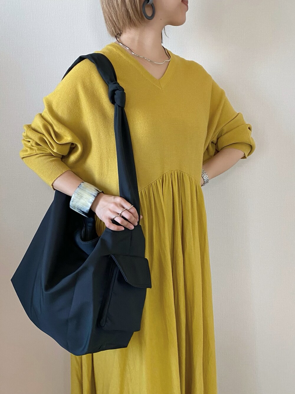 ブラック系のメッセンジャーバッグ、イエロー系のワンピース、ブラック系のスリッポンを着用したレディースの冬コーディネートの3枚目の写真