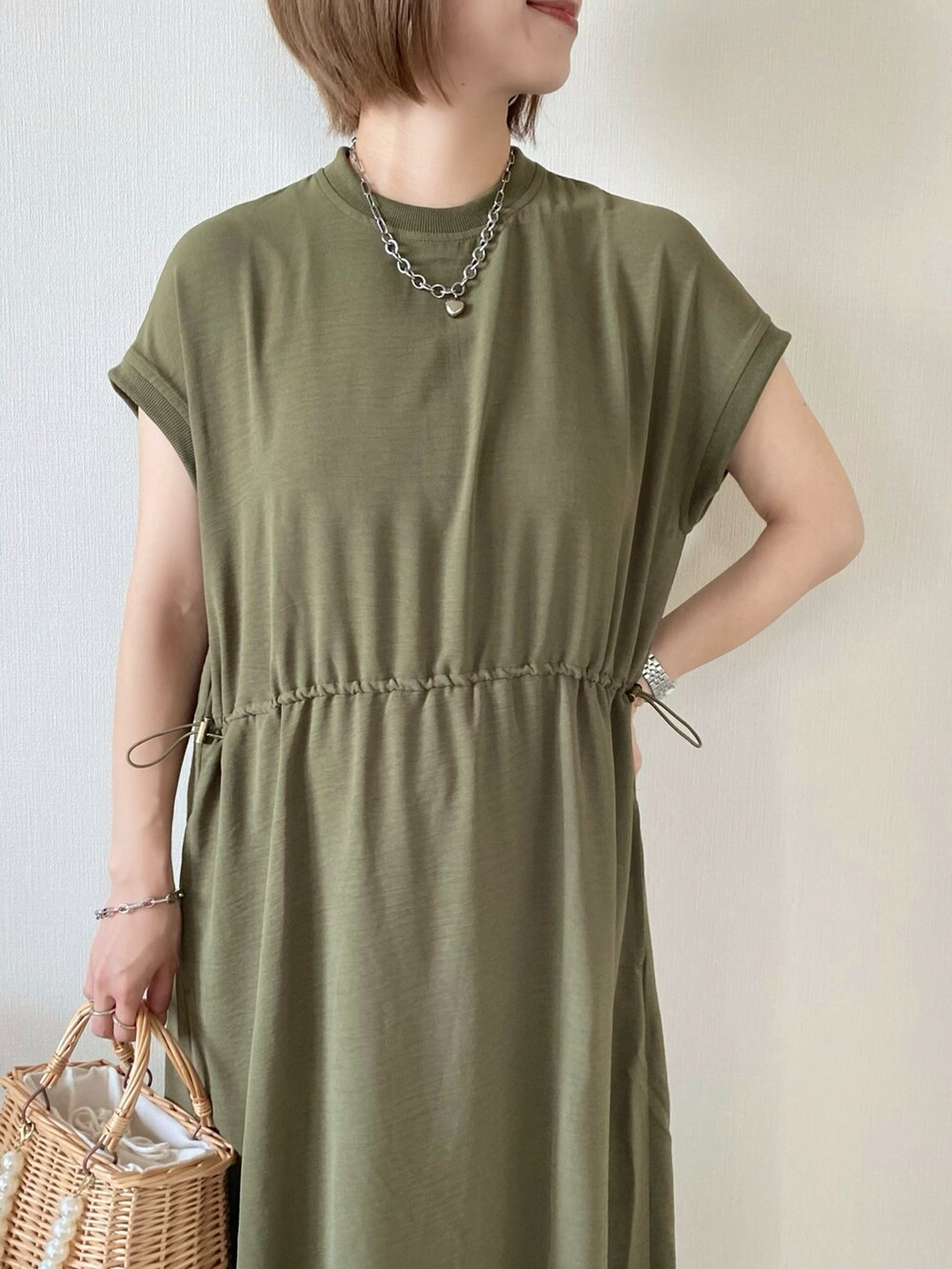 ベージュ系のかごバッグ、グリーン系のワンピース、ピンク系のサンダルを着用したレディースの夏コーディネートの4枚目の写真