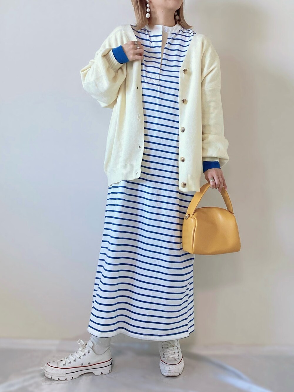 イエロー系のバッグ、ブルー系のワンピース、ホワイト系のスニーカーを着用したレディースの春コーディネートの2枚目の写真