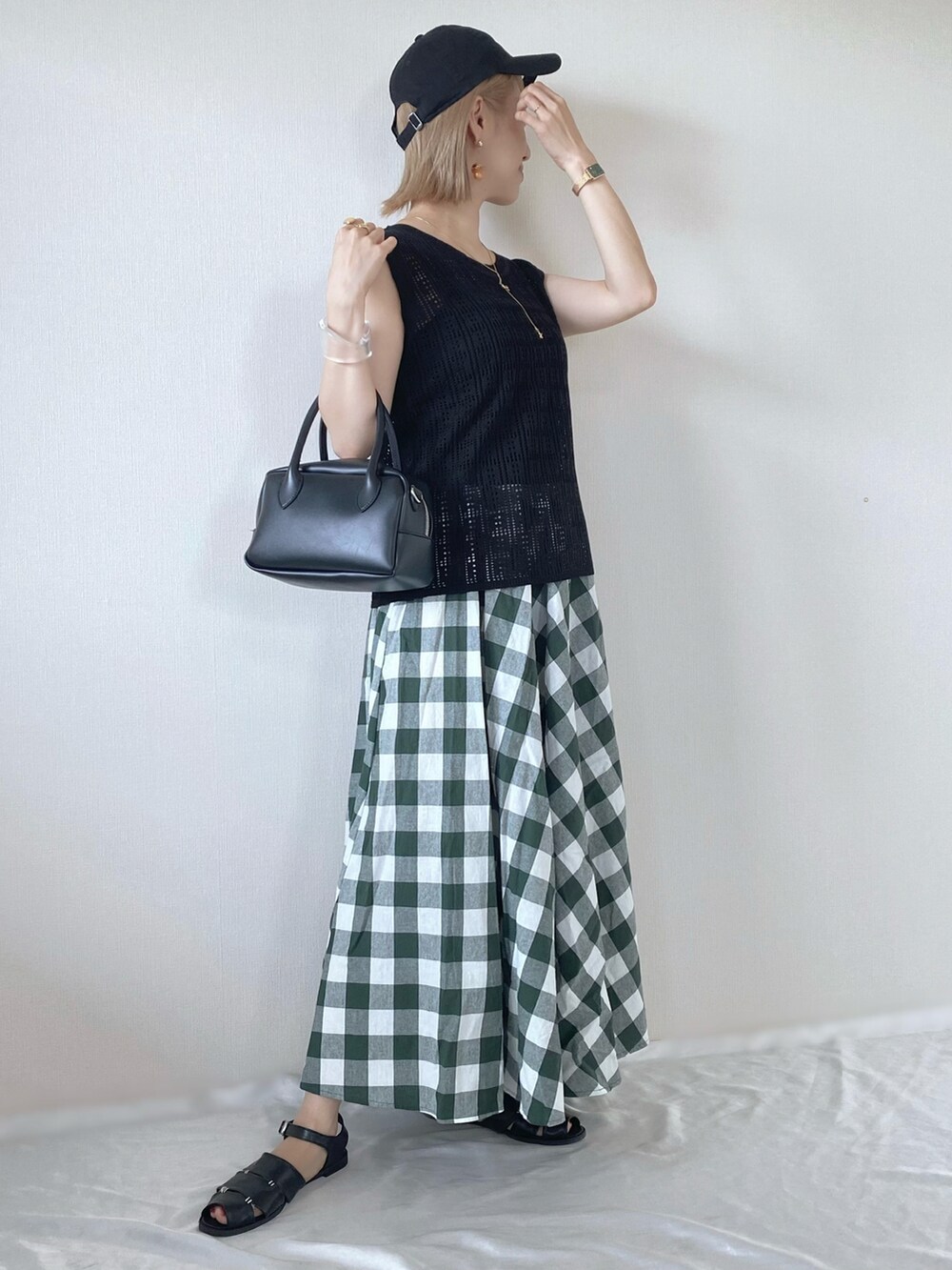 ブラック系のニット/セーター、ブラック系のバッグ、グリーン系のスカートを着用したレディースの春コーディネートの3枚目の写真