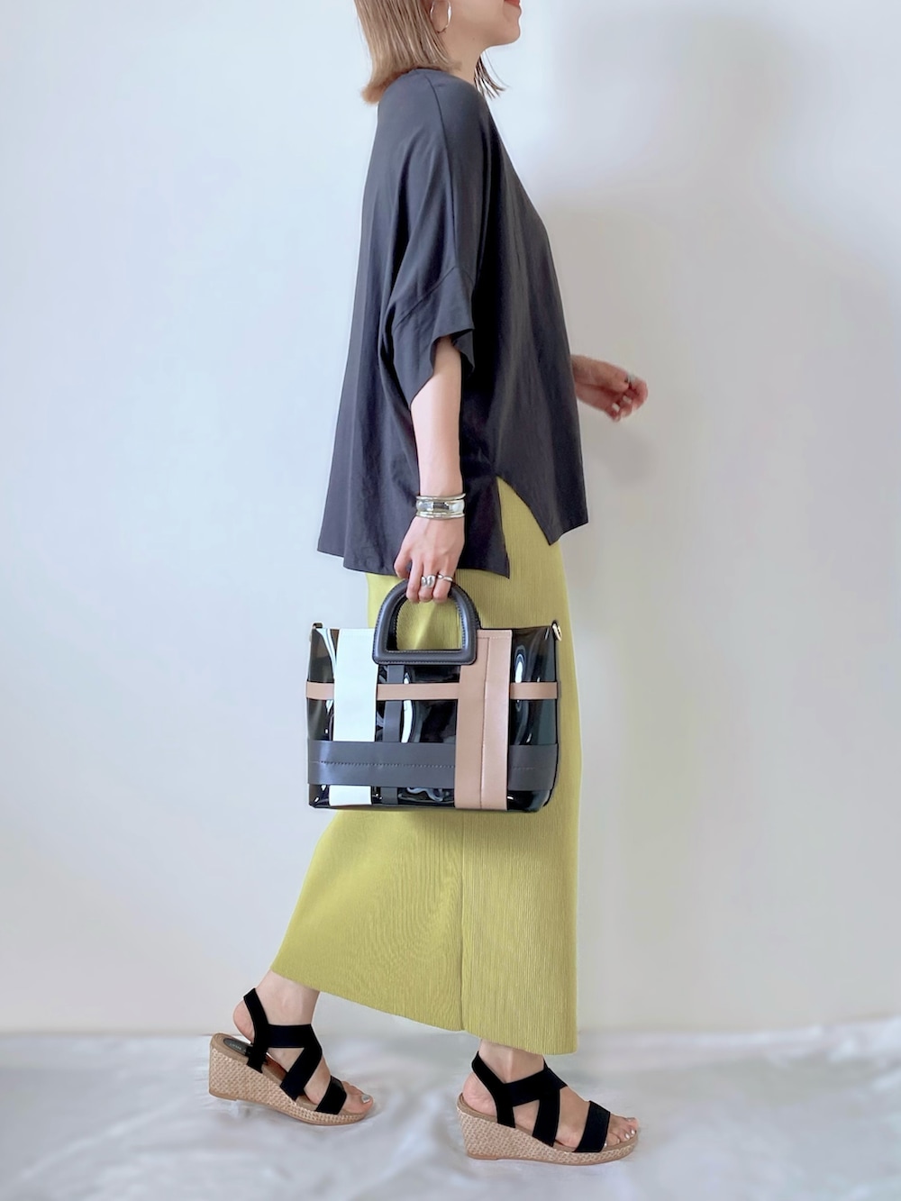 グレー系のTシャツ/カットソー、グリーン系のスカート、ブラック系のバッグを着用したレディースの夏コーディネートの2枚目の写真