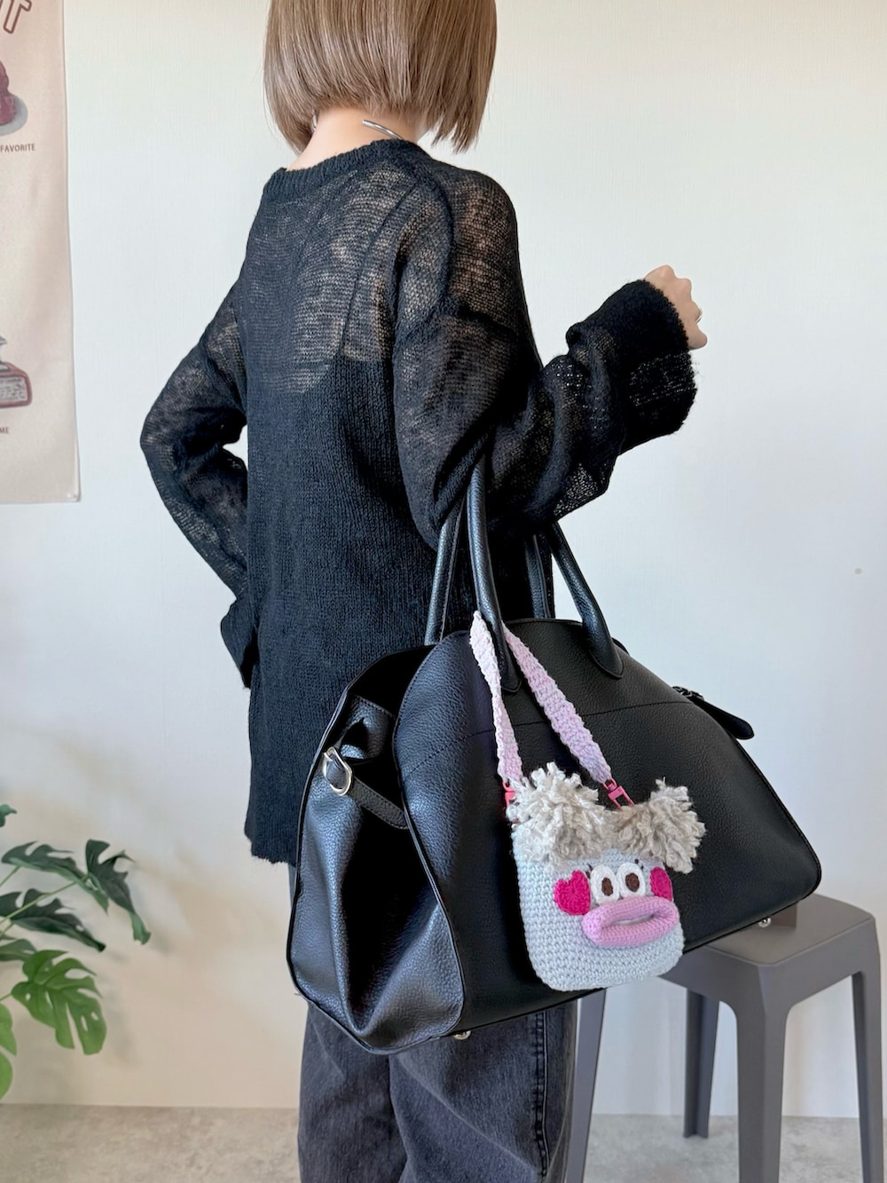 ブラック系のニット/セーター、ブラック系のボストンバッグ、ブラック系のデニムパンツを着用したレディースの冬コーディネートの3枚目の写真