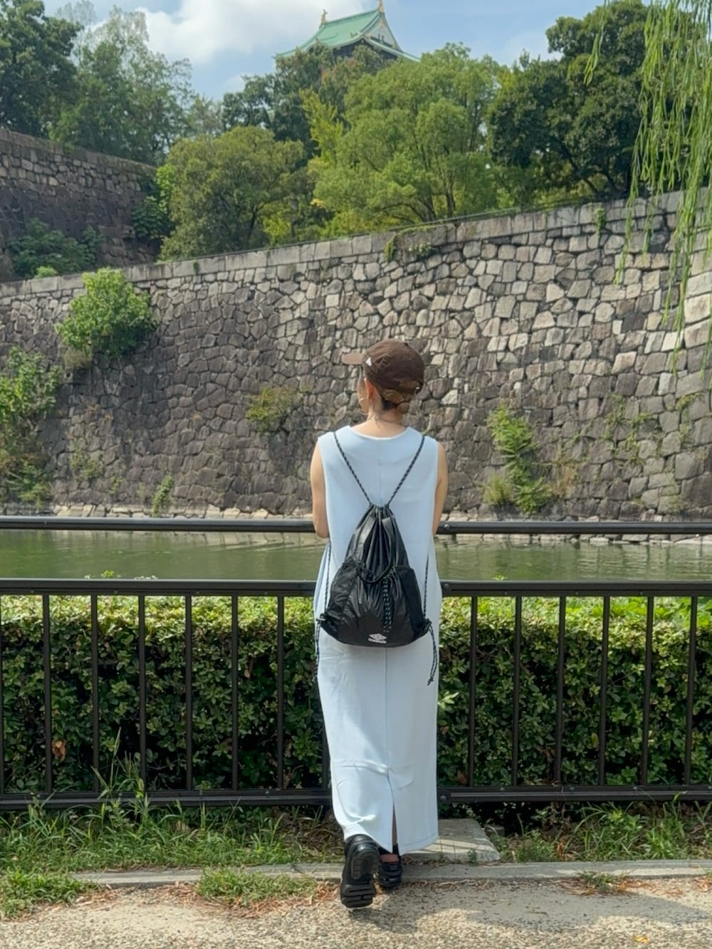 ブラック系のサンダル、ブルー系のジャンパースカート、ブラウン系のキャップを着用したレディースの秋コーディネートの5枚目の写真