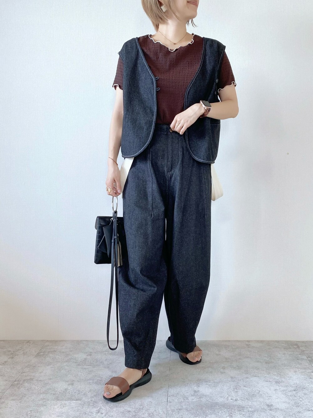 ブラウン系のTシャツ/カットソー、ブラック系のベスト、ブラック系のデニムパンツを着用したレディースの秋コーディネートの2枚目の写真