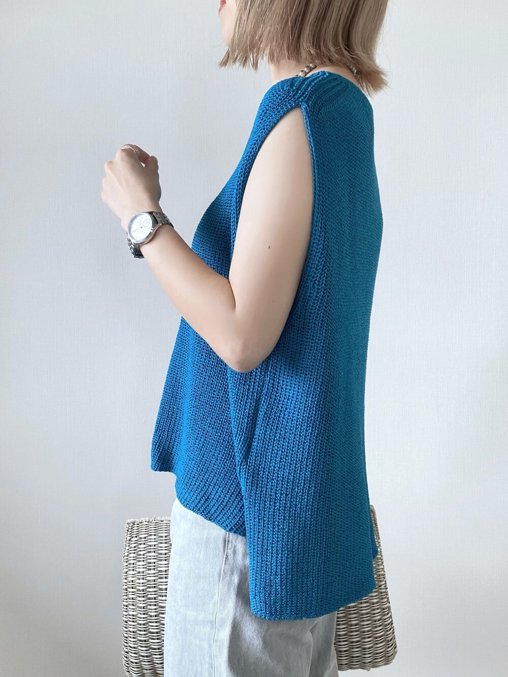 ブルー系のベスト、グレー系のデニムパンツ、ホワイト系のサンダルを着用したレディースの夏コーディネートの4枚目の写真