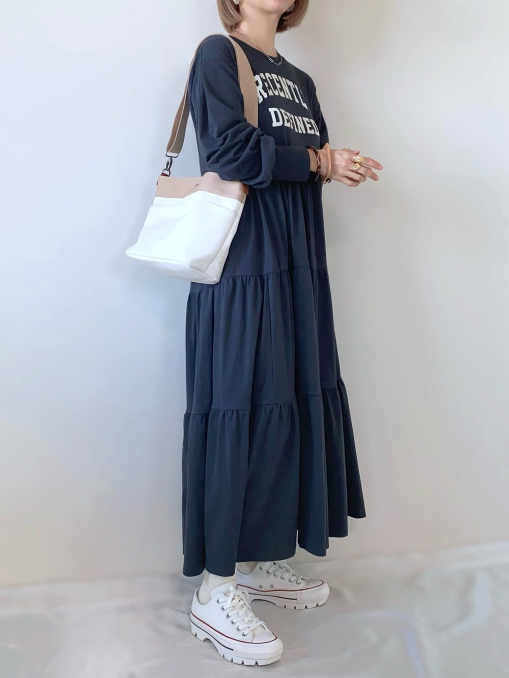 ベージュ系のショルダーバッグ、グレー系のワンピース、ホワイト系のスニーカーを着用したレディースの春コーディネートの2枚目の写真