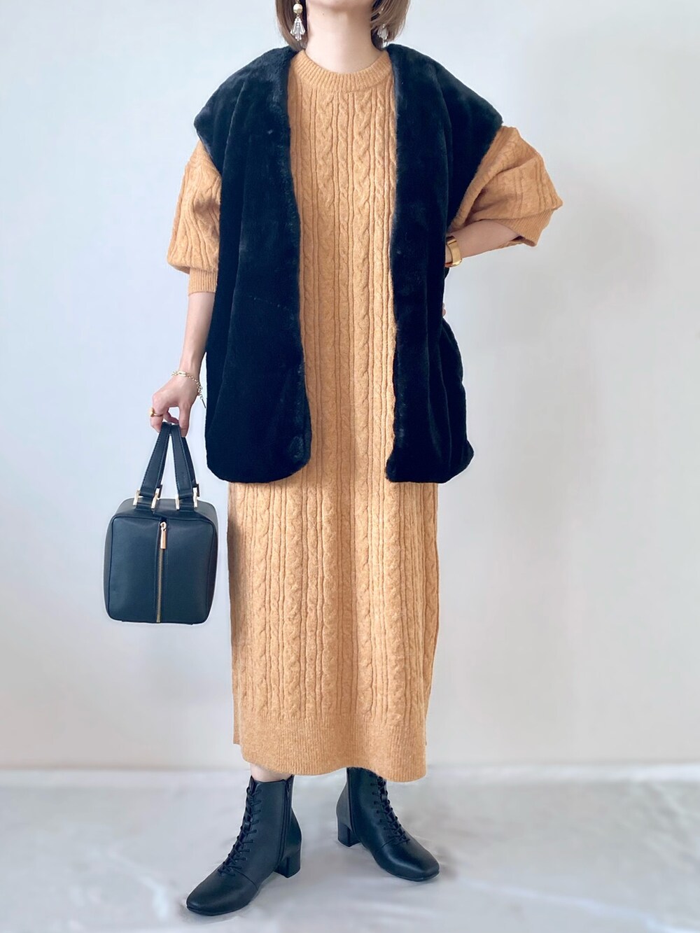 ブラック系のその他アウター、オレンジ系のワンピース、ブラック系のハンドバッグを着用したレディースの秋コーディネートの2枚目の写真