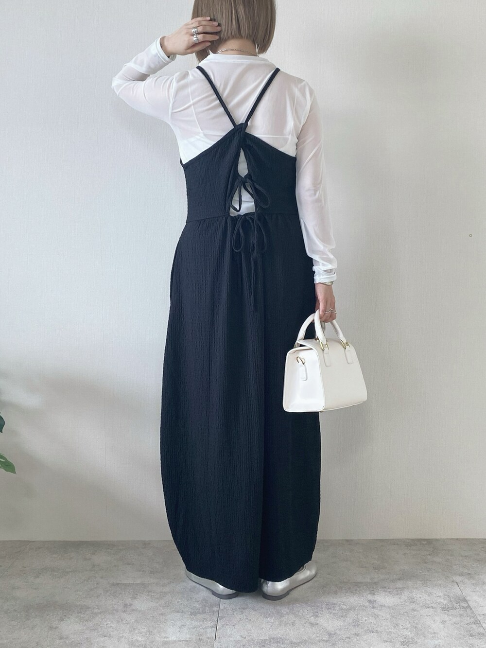 ブラック系のワンピース、ホワイト系のTシャツ/カットソー、ホワイト系のハンドバッグを着用したレディースの春コーディネートの2枚目の写真