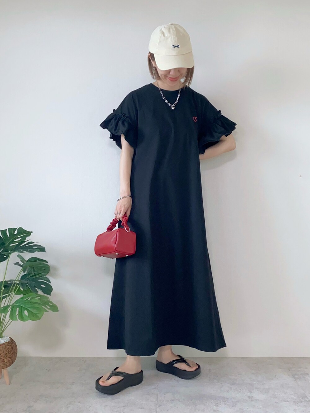 ブラック系のワンピース、レッド系のボストンバッグ、ブラック系のサンダルを着用したレディースの夏コーディネートの2枚目の写真