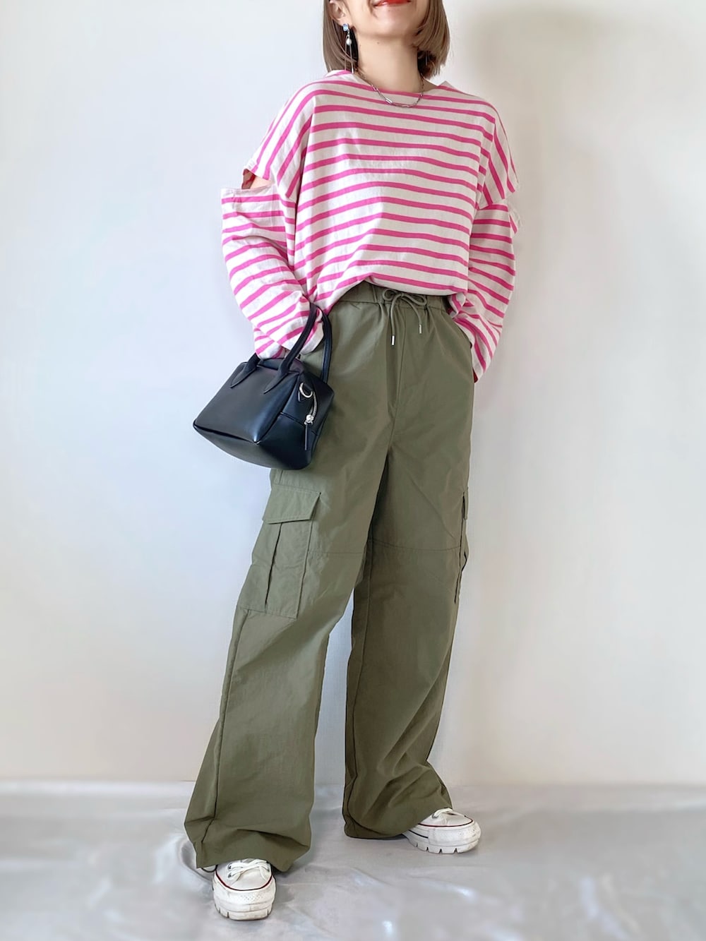 ブラック系のバッグ、グリーン系のカーゴパンツ、ホワイト系のスニーカーを着用したレディースの冬コーディネートの2枚目の写真