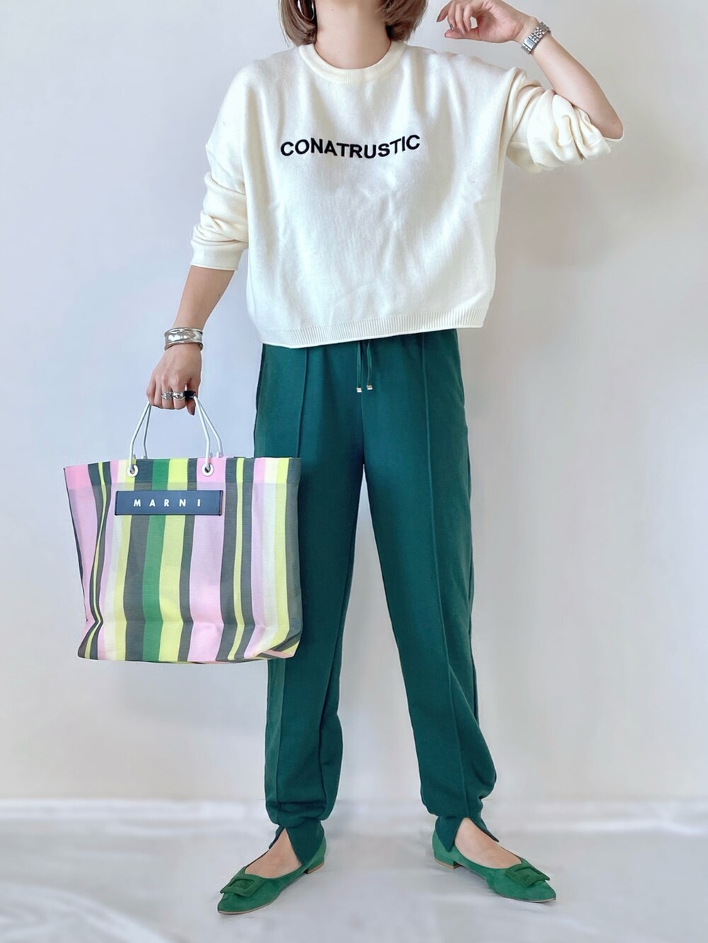 グリーン系のトートバッグ、グリーン系のパンプス、ホワイト系のニット/セーターを着用したレディースの秋コーディネートの3枚目の写真