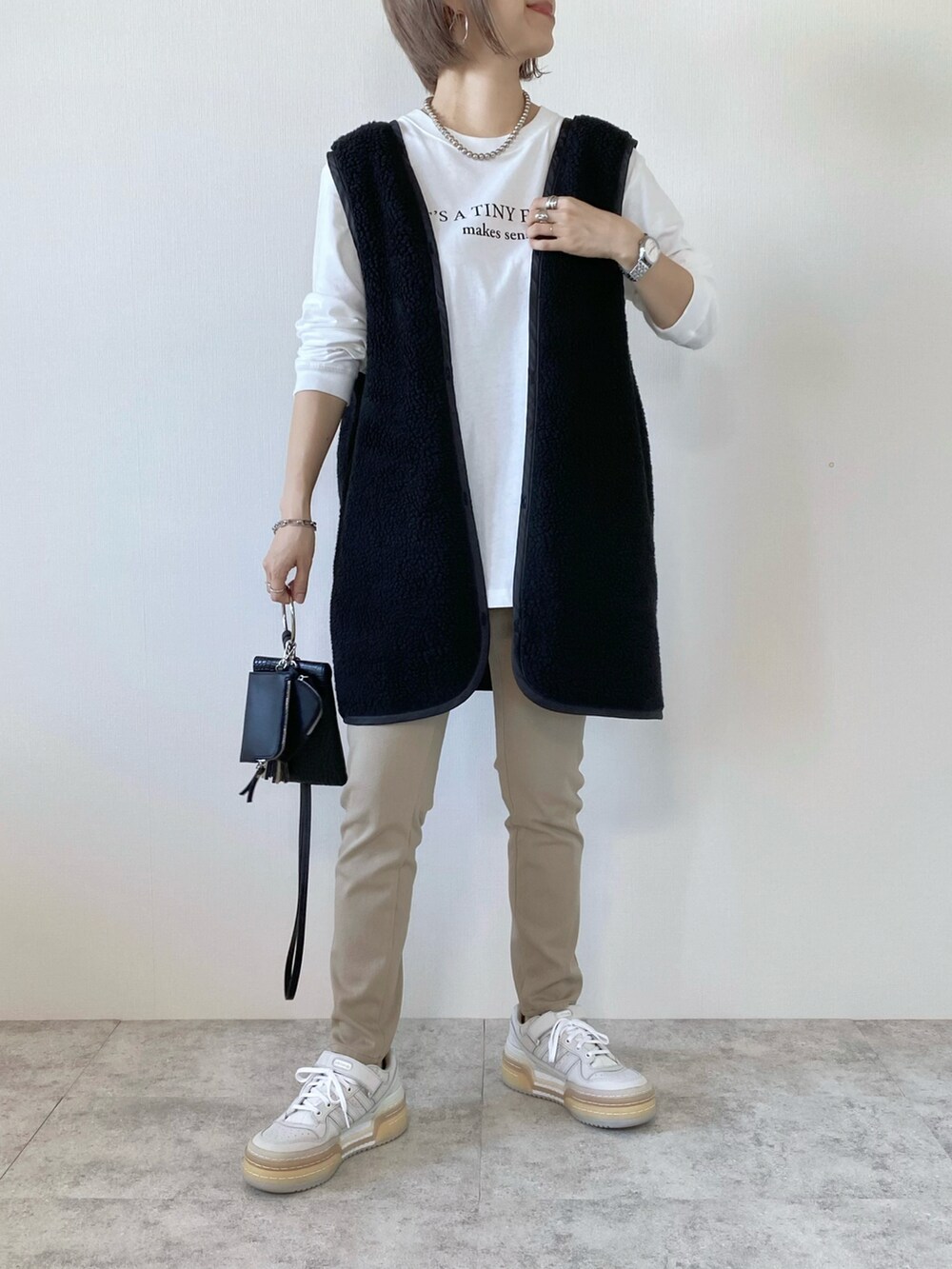 ホワイト系のスニーカー、ブラック系のショルダーバッグ、その他のTシャツ/カットソーを着用したレディースの秋コーディネートの4枚目の写真