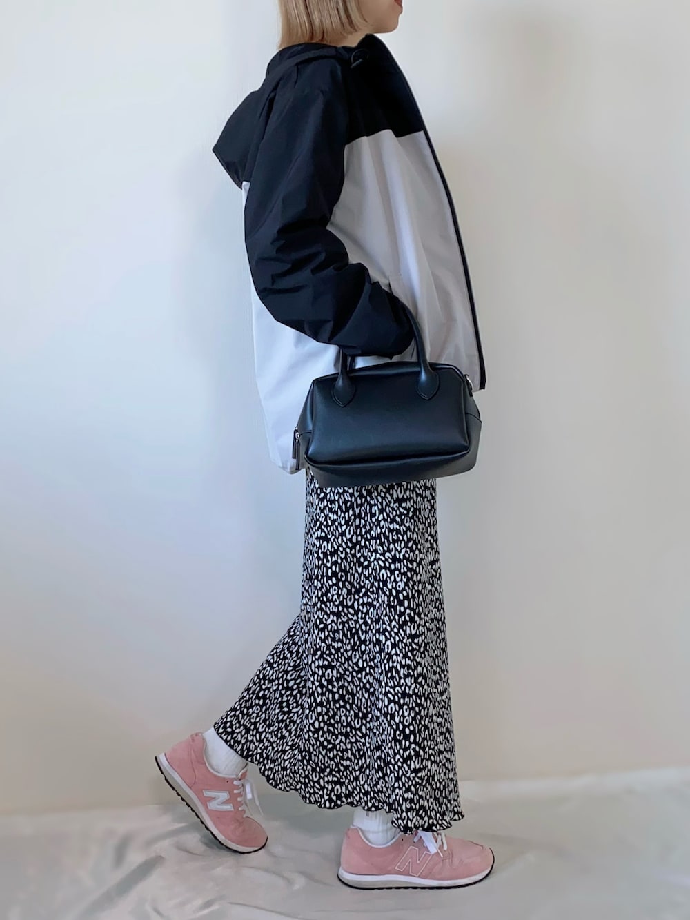 ブラック系のバッグ、ブラック系のスカート、ベージュ系のマウンテンパーカーを着用したレディースの春コーディネートの2枚目の写真