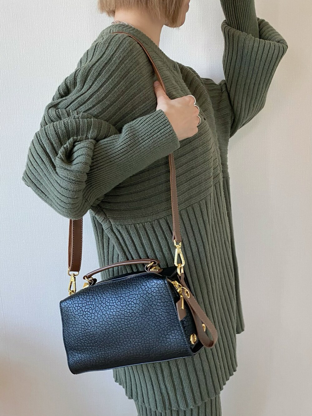 ブラック系のボストンバッグ、グリーン系のニット/セーター、ブラック系のパンプスを着用したレディースの冬コーディネートの3枚目の写真