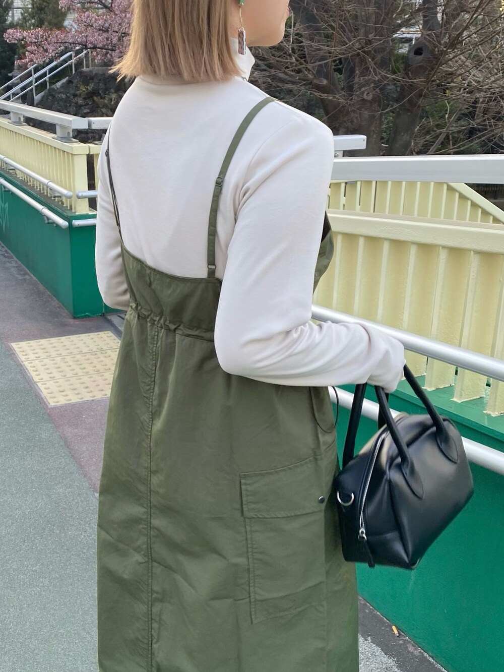 ブラック系のバッグ、グリーン系のワンピース、ホワイト系のスニーカーを着用したレディースの春コーディネートの5枚目の写真
