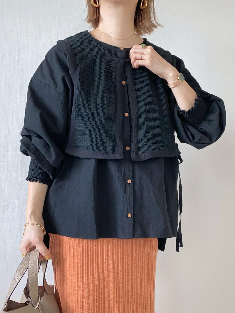 オレンジ系のスカート、ベージュ系のローファー、ブラック系のシャツ/ブラウスを着用したレディースの春コーディネートの3枚目の写真