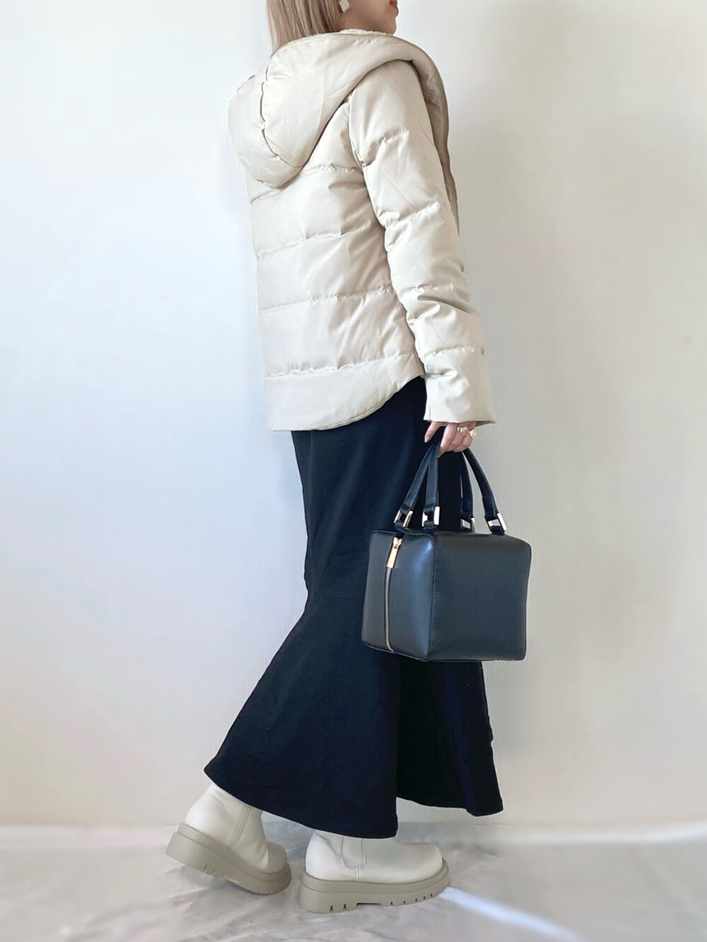 ブラック系のワンピース、ブラック系のハンドバッグ、ホワイト系のブーツを着用したレディースの秋コーディネートの2枚目の写真