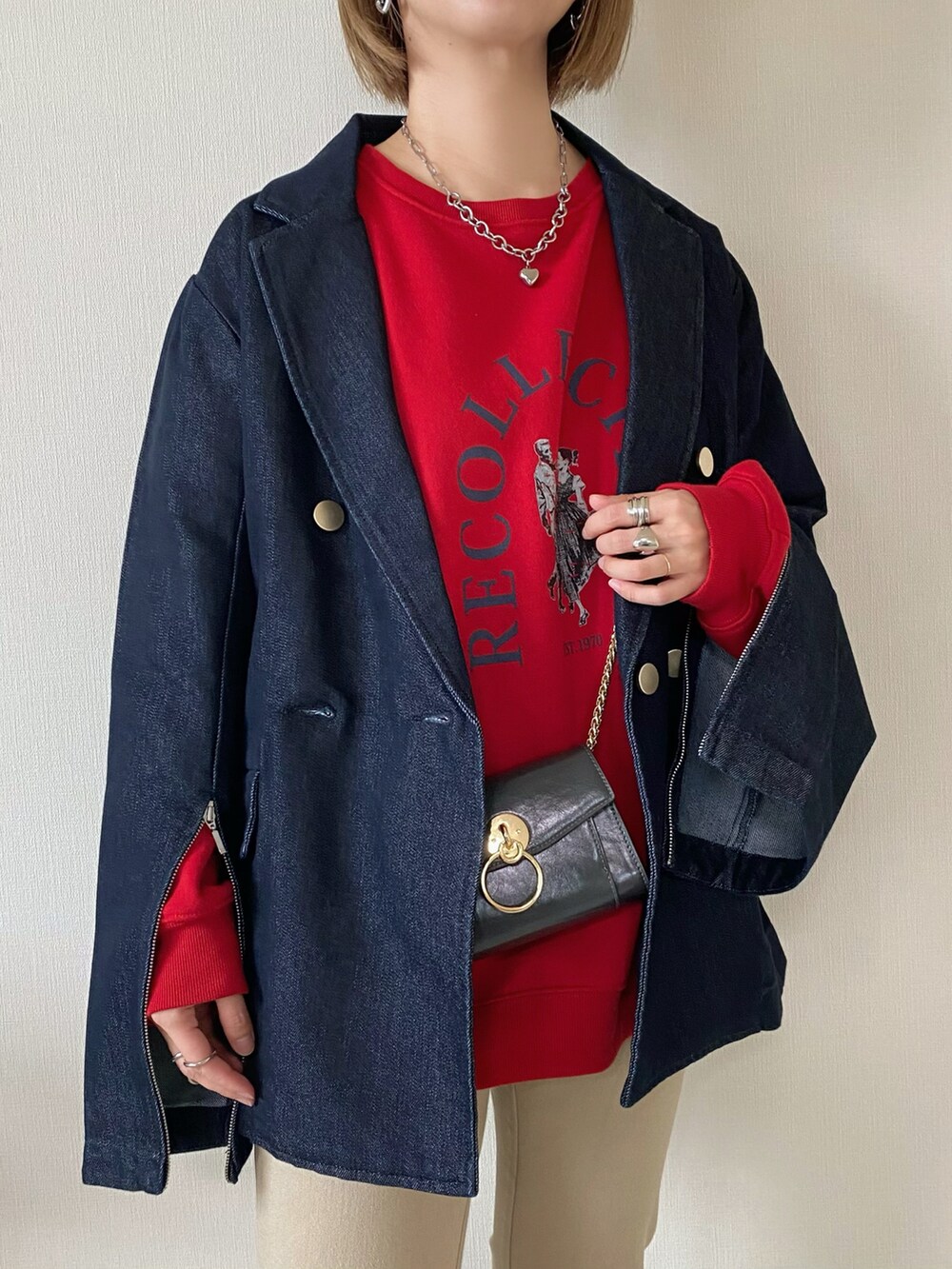 レッド系のスウェット、ブルー系のデニムジャケット、ブラック系のパンプスを着用したレディースの春コーディネートの3枚目の写真