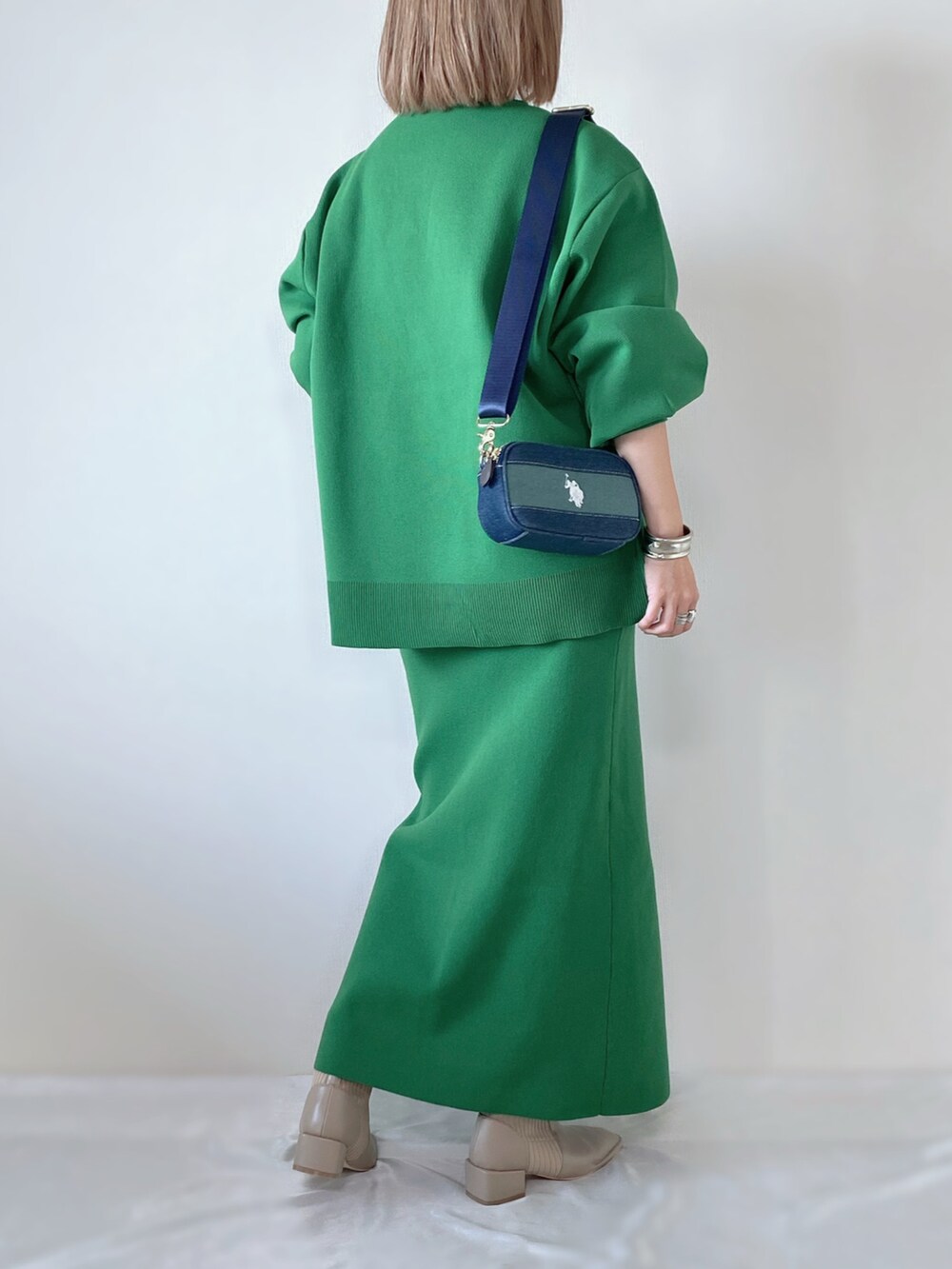 グリーン系のニット/セーター、グリーン系のスカート、ベージュ系のブーツを着用したレディースの秋コーディネートの3枚目の写真