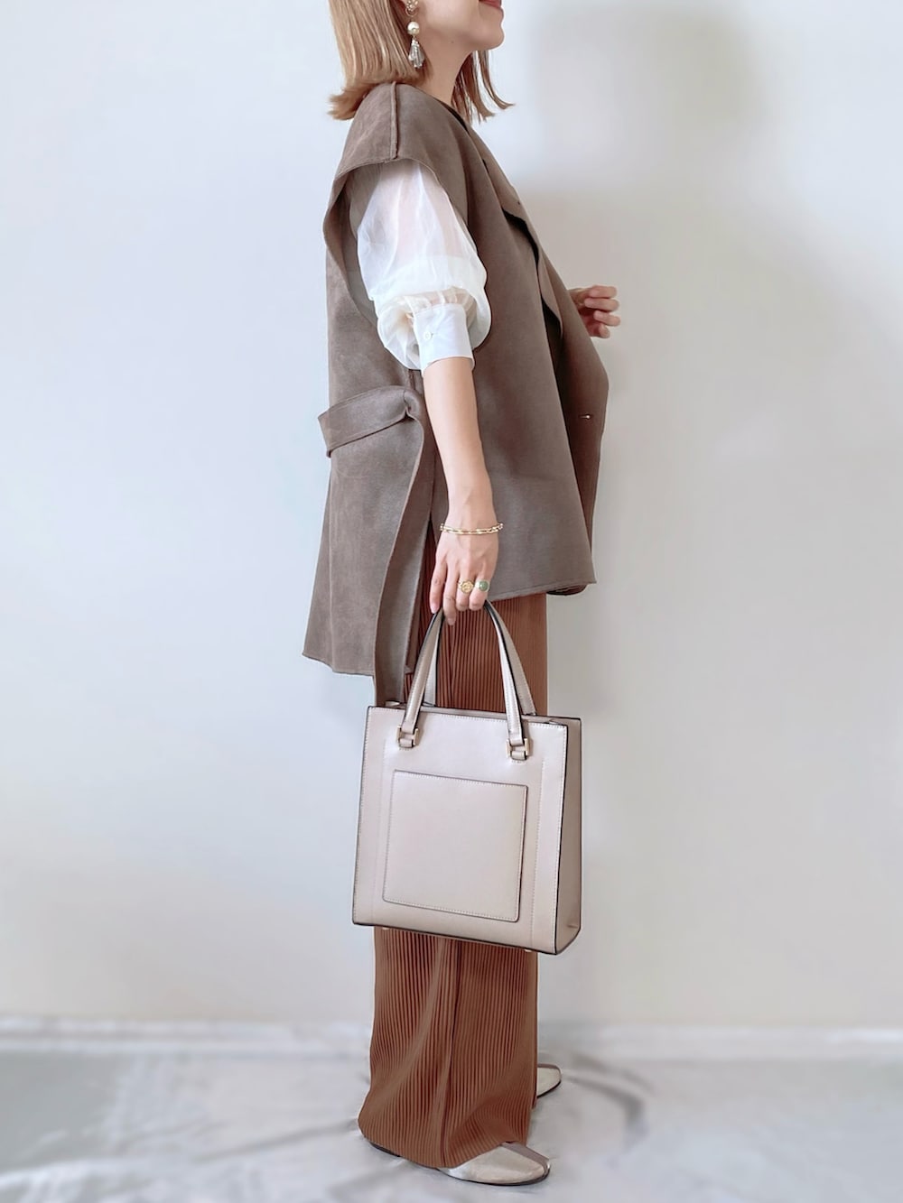 ベージュ系のベスト、ホワイト系のシャツ/ブラウス、ベージュ系のパンツを着用したレディースの秋コーディネートの3枚目の写真