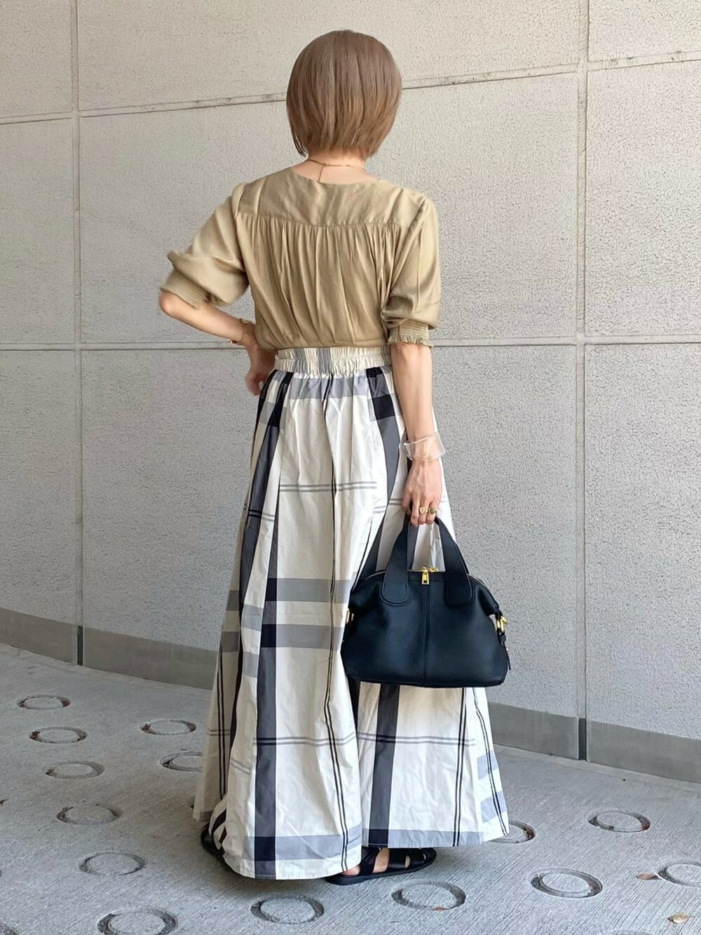 イエロー系のシャツ/ブラウス、ホワイト系のスカート、ブラック系のバッグを着用したレディースの夏コーディネートの2枚目の写真