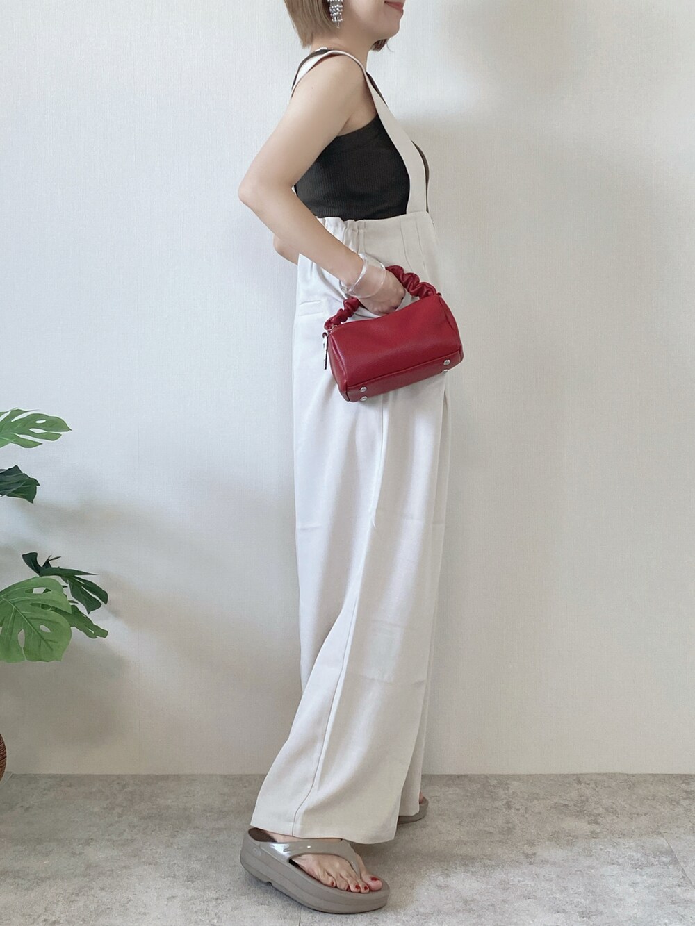 レッド系のボストンバッグ、ベージュ系のサロペット/オーバーオール、ベージュ系のサンダルを着用したレディースの夏コーディネートの2枚目の写真