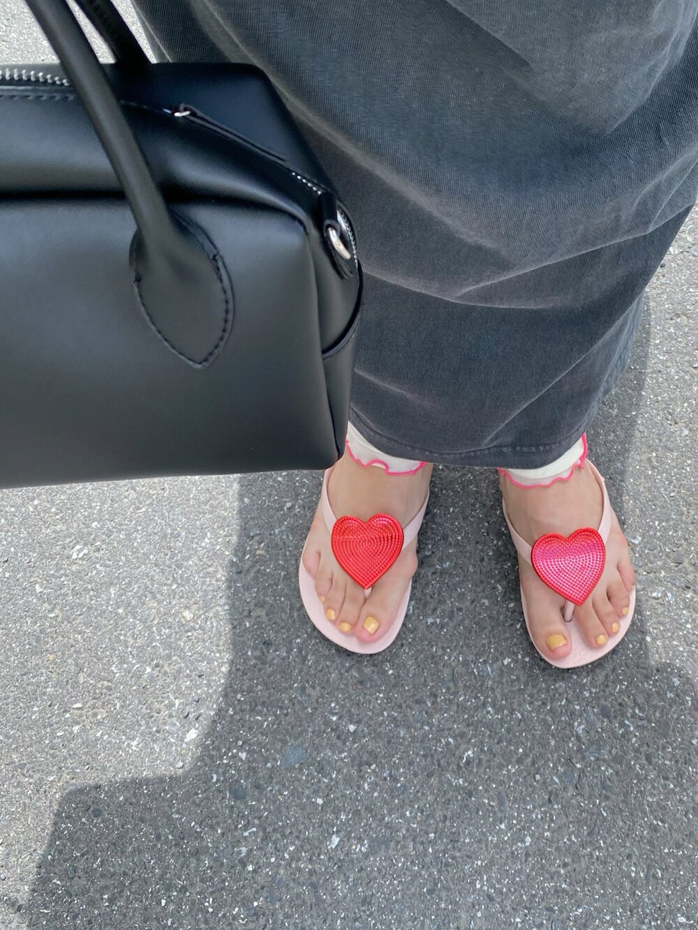 ピンク系のサンダル、ブラック系のバッグ、シルバー系のピアス（両耳用）を着用したレディースの夏コーディネートの3枚目の写真