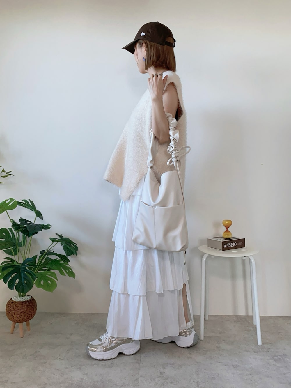 ホワイト系のベスト、ゴールド系のスニーカー、ホワイト系のスカートを着用したレディースの秋コーディネートの3枚目の写真